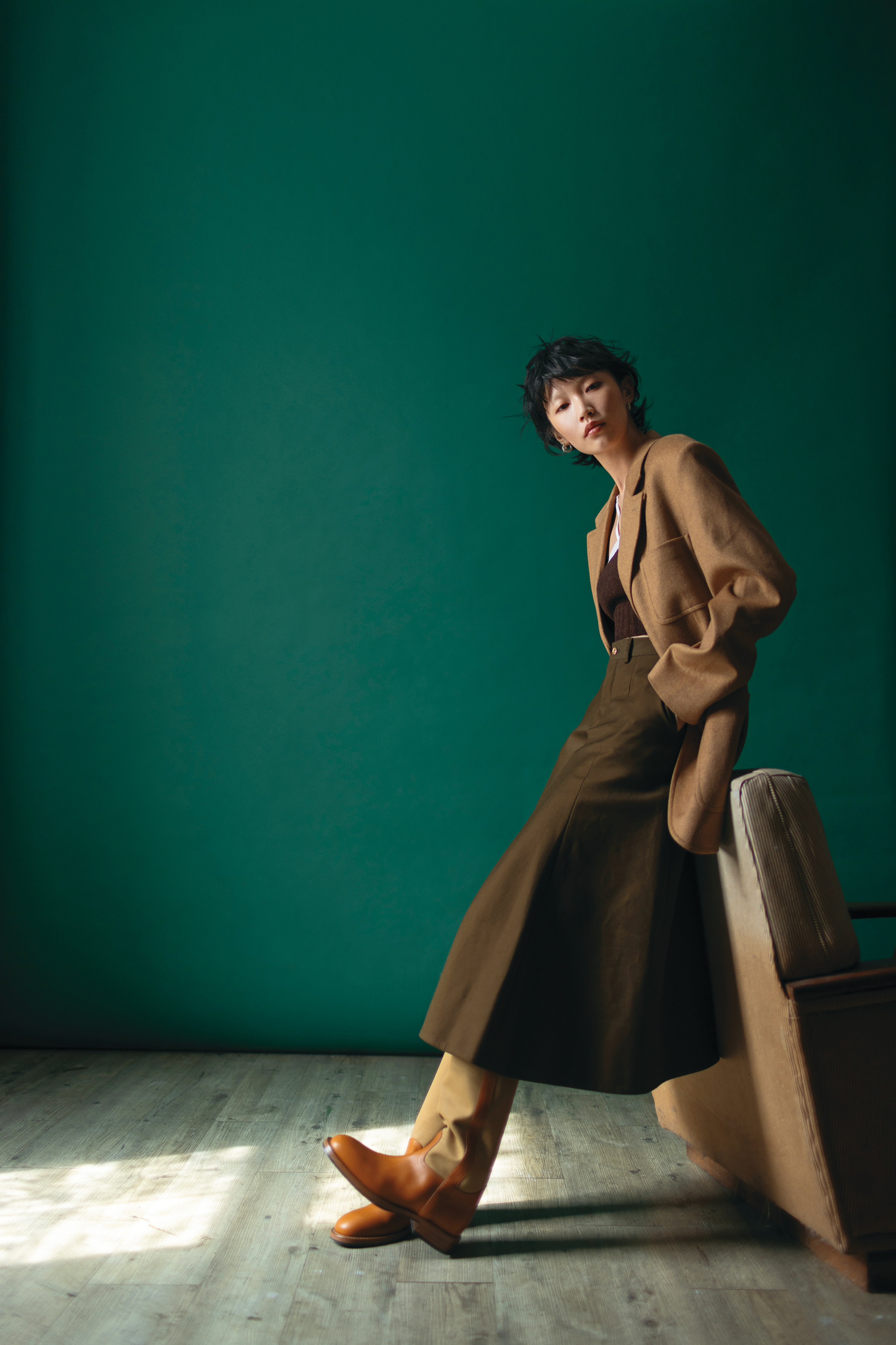 棕色外套 價格店洽 by CELINE／短版針織背心 價格店洽 by PRADA／棕綠色毛料過膝裙 價格店洽 by CELINE／拼接材質長靴 價格店洽 by Loro Piana／銀色耳環 價格店洽 by CELINE