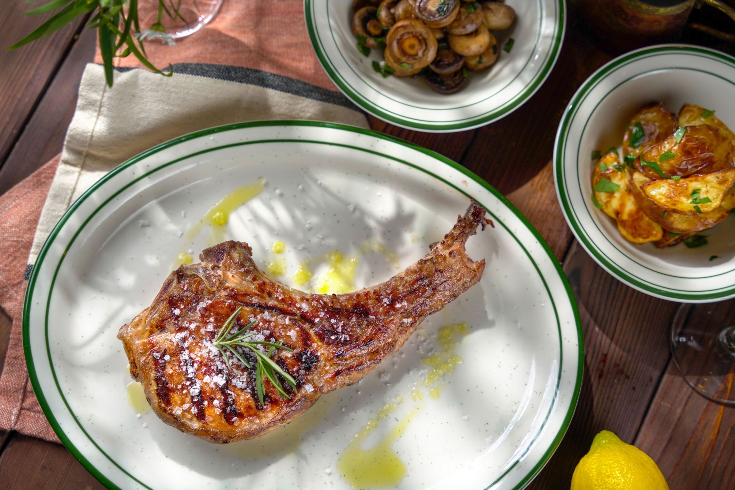 君品酒店Ciao西西里牛排餐酒館推出「盛夏碳烤海陸拼盤季」，雙人組合價2,380元+10%起，碳烤黑豬帶骨豬排外香內嫩，展現濃郁碳烤風味。（雲朗觀光提供）