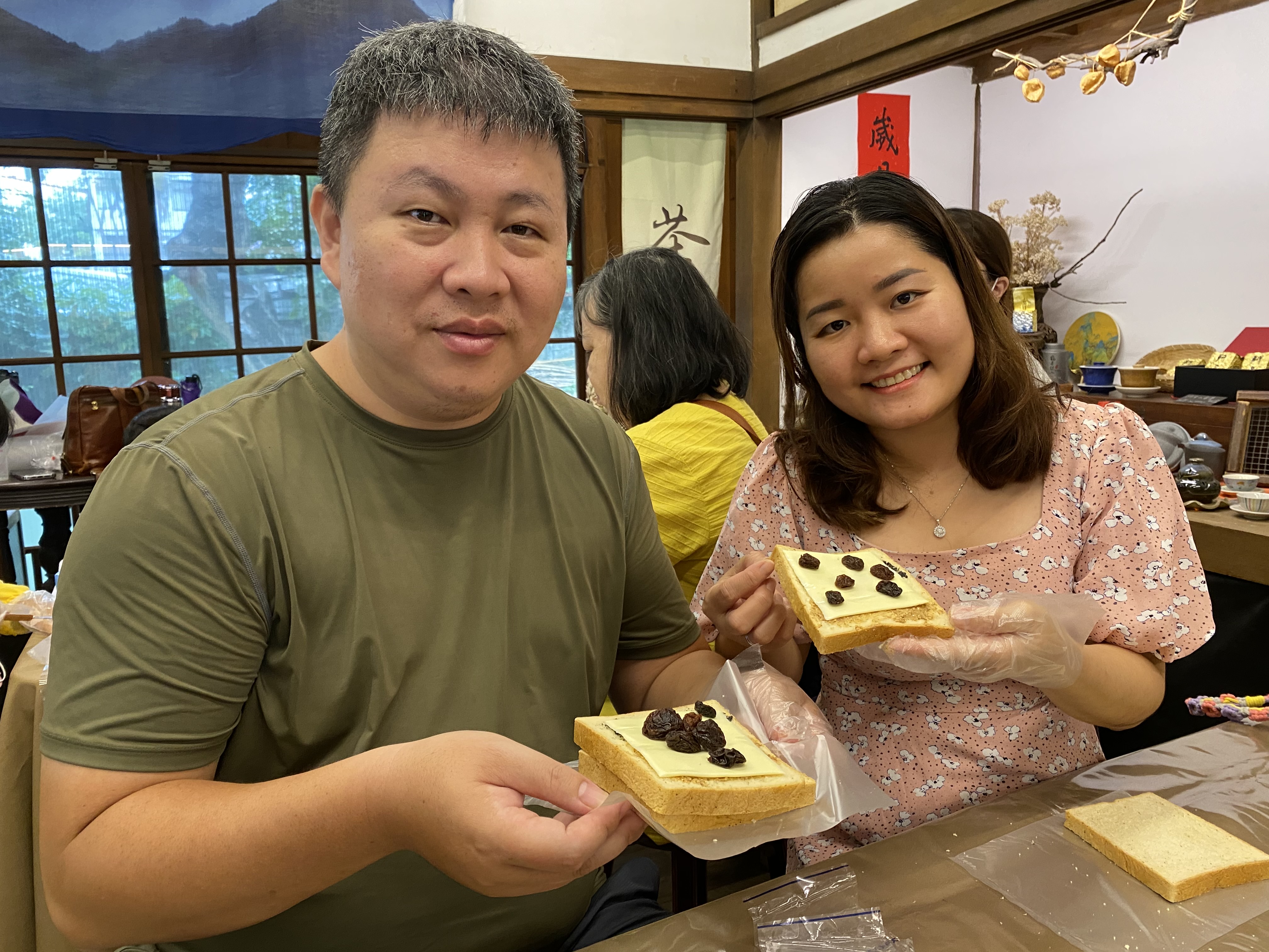越南新住民紅青（右）和丈夫開心地展示手作健康三明治。（移民署提供）