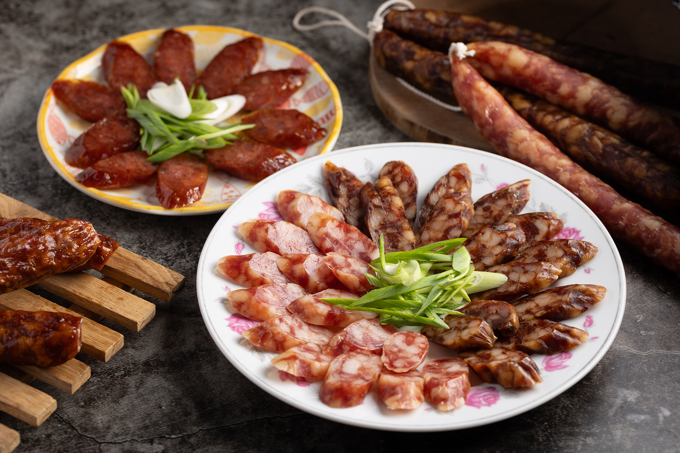 「廣東臘腸與肝腸」（前，400元／斤）酒香優雅，肝腸脂香濃厚，是煲仔飯首選；「四川辣香腸」（後，420元／斤）以生鮮台灣豬製作，迷人麻辣風味讓人一吃就愛上。