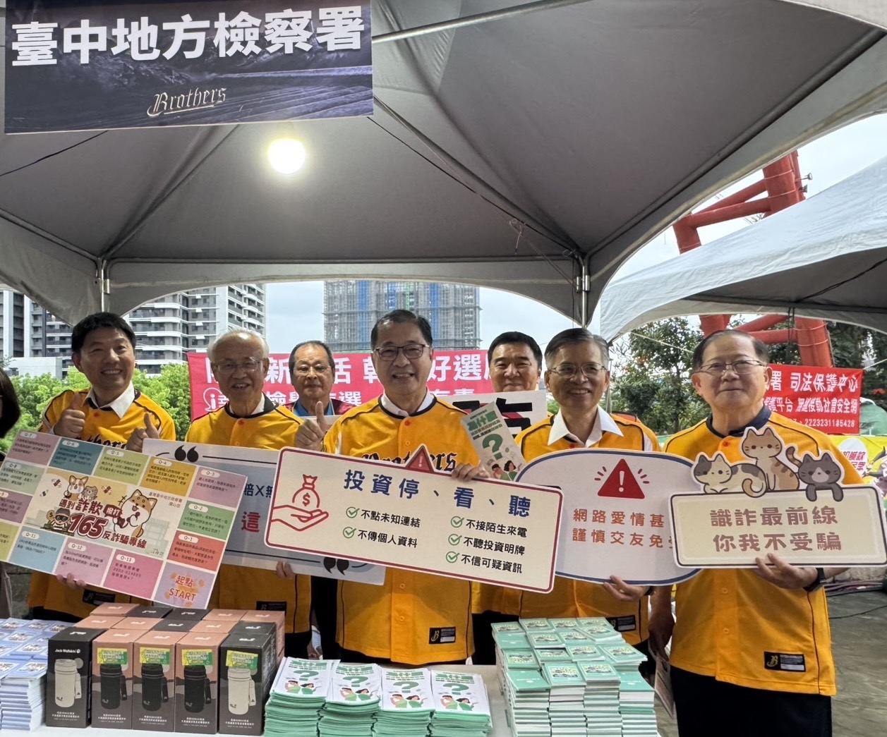 法務部鄭銘謙部長(圖中)到洲際球場宣導打詐反毒反賄選,在反詐詐宣導攤位前以標語提醒民眾打詐重要性。(中信兄弟提供)