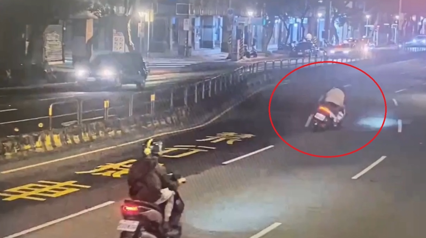 警方調閱監視器，發現機車騎士（紅圈）不明原因車身搖晃失控自摔。（翻攝畫面）