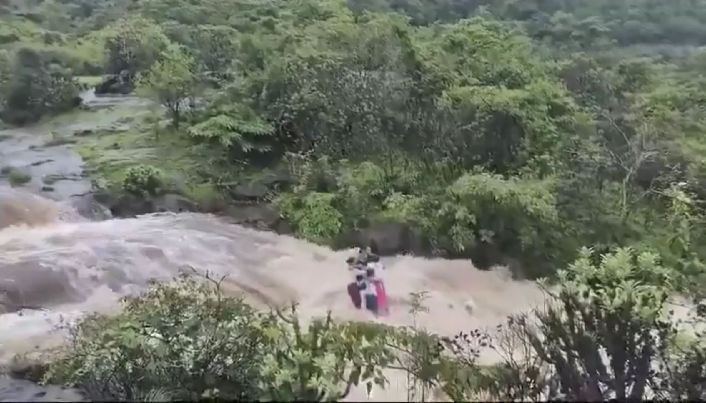 1家7口站在石頭上,努力抗衡水流。(翻攝自X)