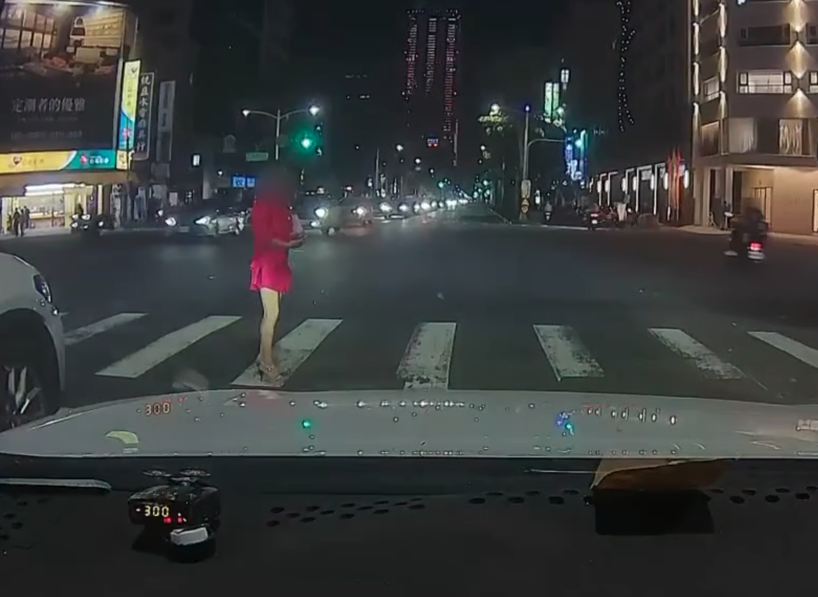 一名女子日前違規闖紅燈穿越馬路，直愣愣地盯著禮讓自己的汽車駕駛。（翻攝臉書「八卦村 - 行車紀錄器影片上傳中心」）
