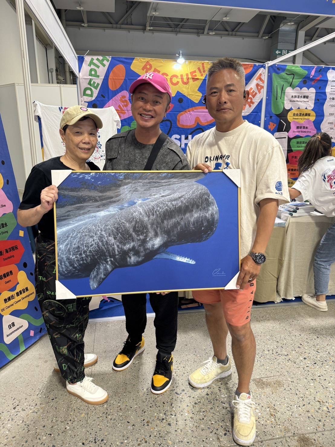 美秀創意執行長楊美秀(左起)、彈頭送上潛水時拍攝的作品給黃春源。(美秀創意提供)