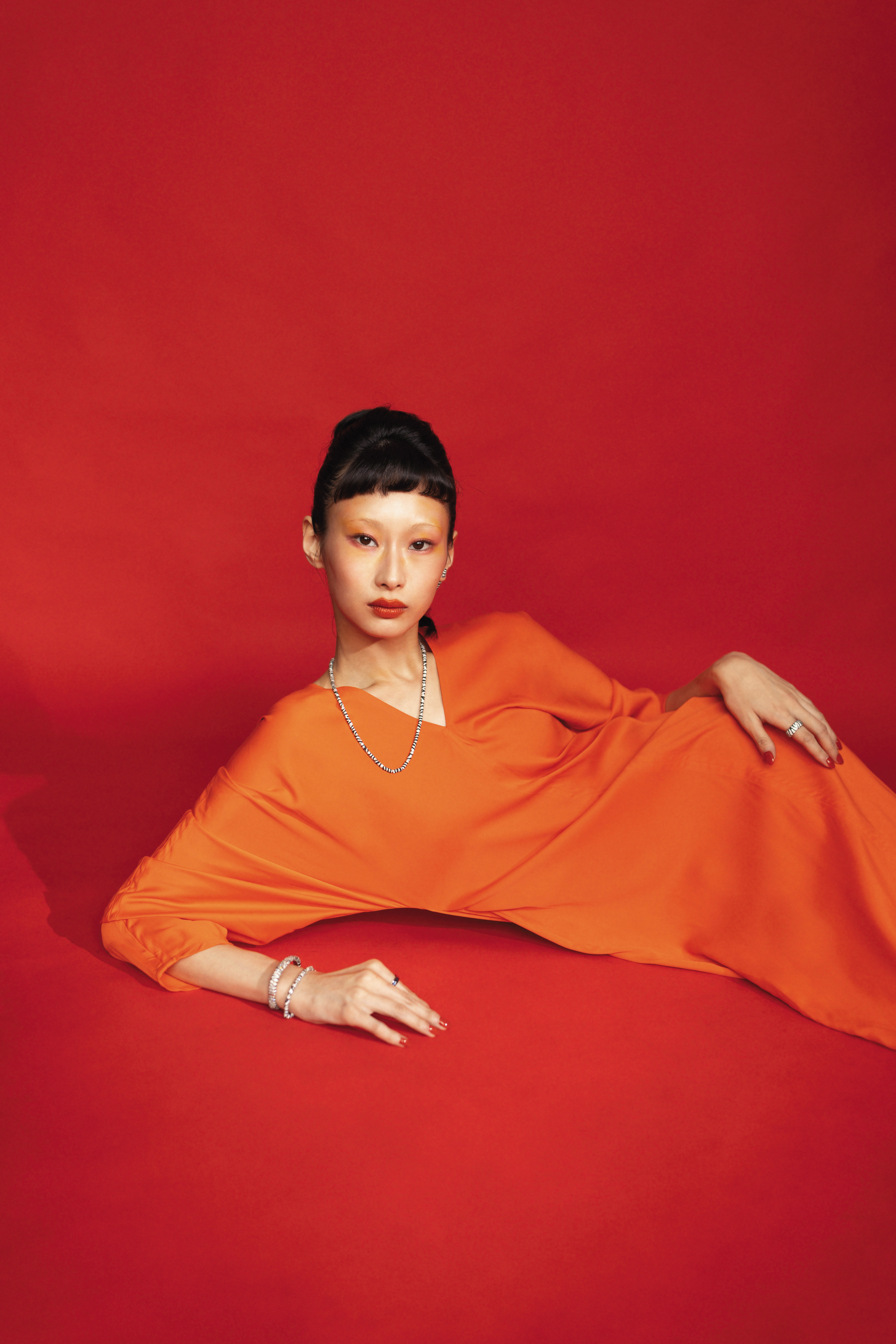 緞面橘色長袖洋裝 NT$80,900 by FERRAGAMO；單隻斑馬垂下耳環 NT$5,500 by APM MONACO；斑馬可調節項鍊 NT$15,500 by APM MONACO；斑馬手鍊 NT$8,600 by APM MONACO；斑馬手鐲 NT$14,500 by APM MONACO；粗斑馬戒指 NT$7,600 by APM MONACO；SMILE藍色摩斯密碼戒指 NT$3,300 by APM MONACO。