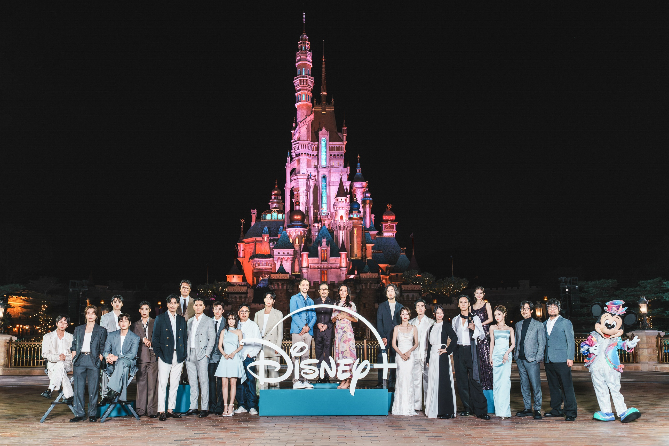 串流平台Disney+原創內容發布會今年移師至香港迪士尼度假區舉行，參與原創作品的日、韓、美影人在園區內城堡前與米奇留影。（Disney+提供）