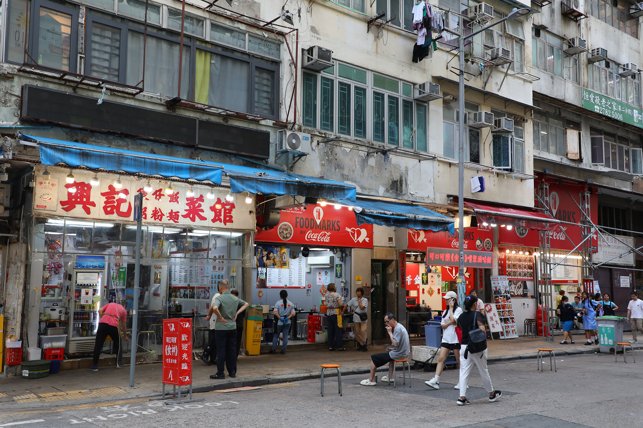 當街燈亮起，佔據整條街的「興記菜館」的炭爐也隨之熱烈燃燒，這裡不僅是餐廳，更是廟街近50年不變的街頭味道。