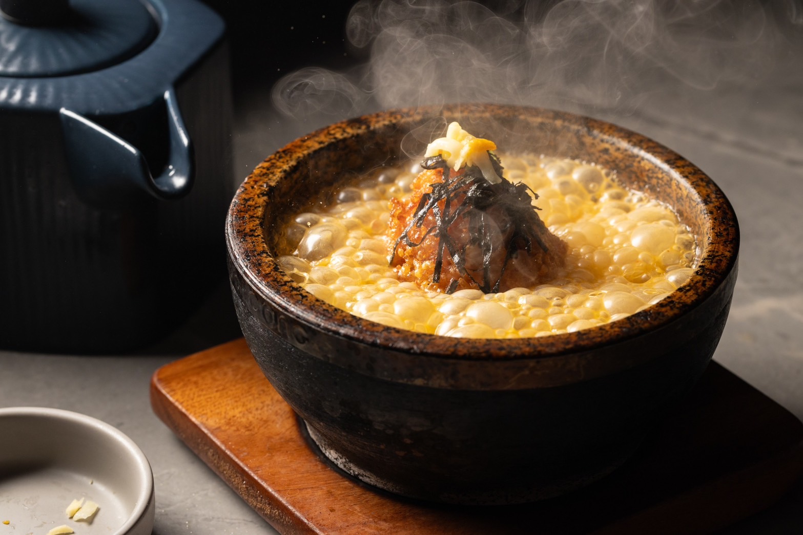 「火山爆發烤飯糰」是將特製湯底倒入裝有烤飯糰的熱石鍋中，打造出瞬間煙霧瀰漫的戲劇效果。（套餐可加價更換79元／份）