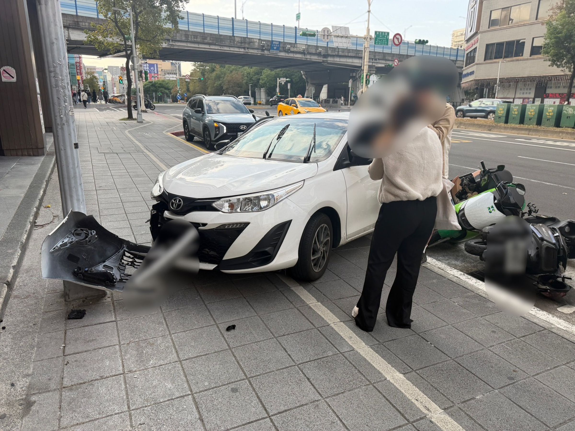 台北市南京東路昨日發生白車暴衝開上人行道事故,該車撞上燈桿後車頭水箱護罩全毀。(翻攝畫面)