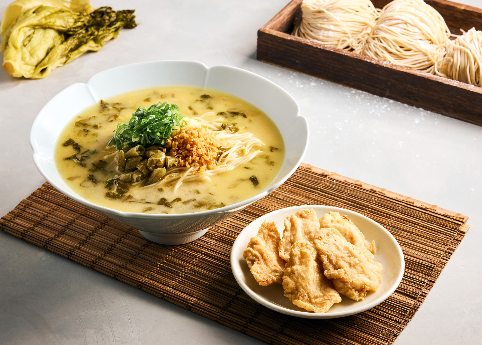 「酸菜金黃魚片雞白湯麵」湯汁辛口、尾韻香甜，油炸的多利魚片，外酥內軟。（288元／碗，圖片由樂蝦拉麵提供）