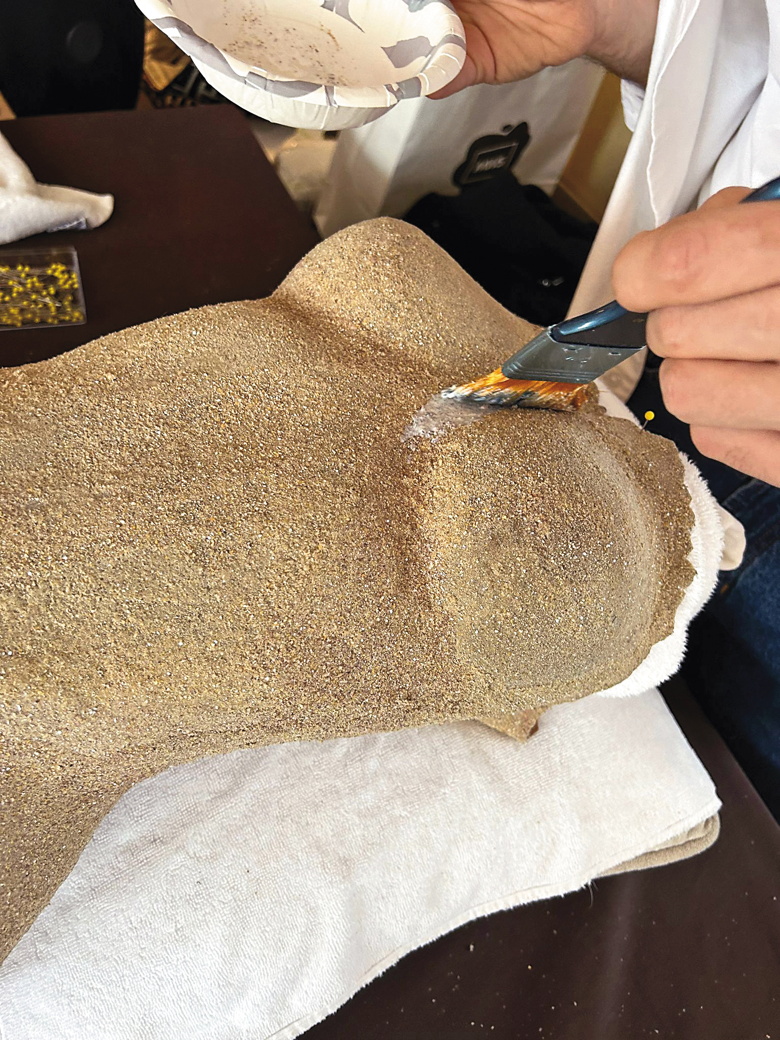 在費盡心力用沙子堆出輪廓後,還得仔細刷上一層膠,維持沙裙樣貌。(美之心提供)