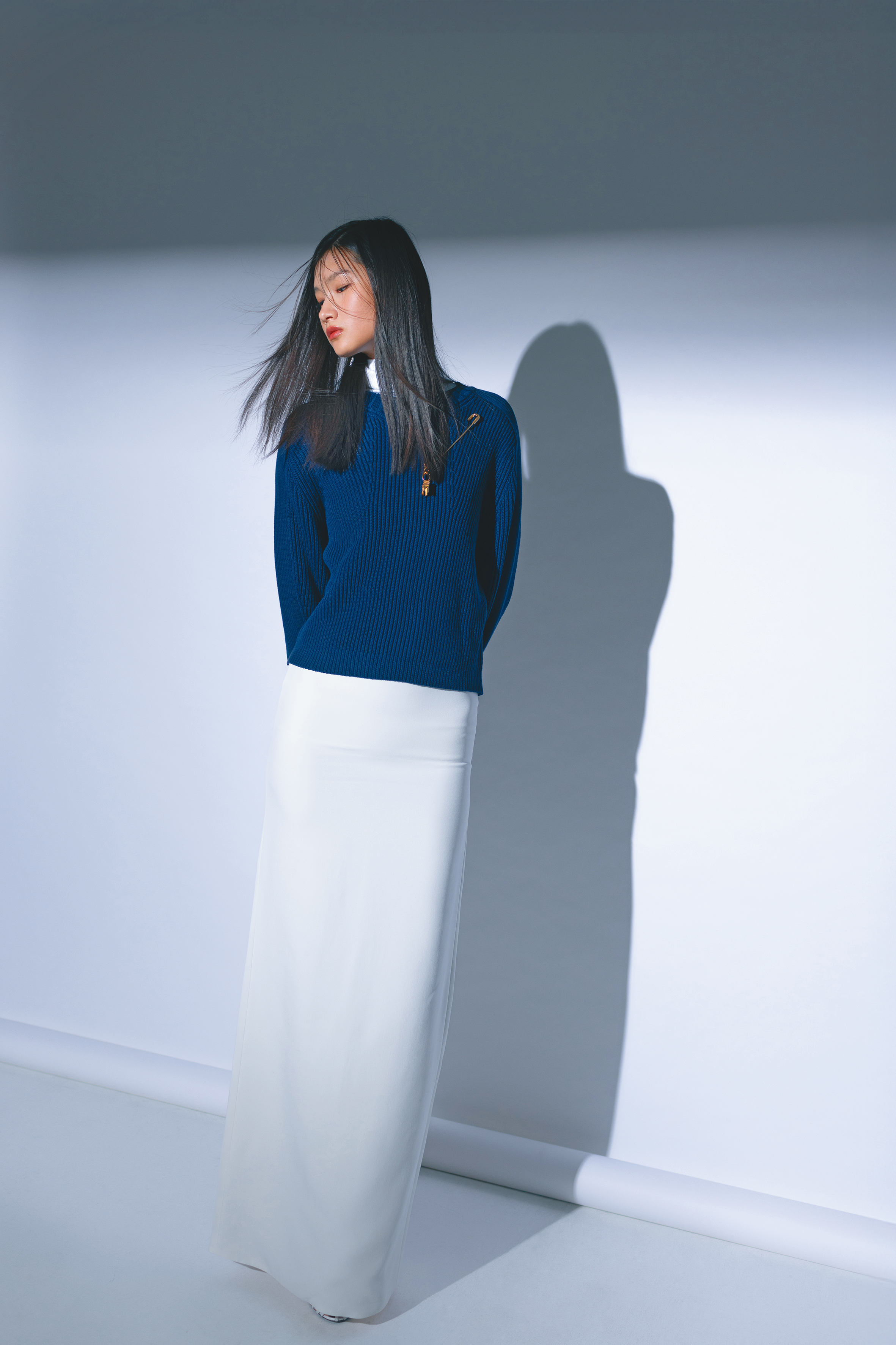 深藍色棉質針織衫 NT$13,400 by MAX&Co.；白色高領 NT$29,000 by CELINE；白色長裙 價格店洽 by CELINE；TRIOMPHE涼鞋 價格店洽 by CELINE；CELINE CHARMS金色飾面安全扣針胸針 NT$11,500 by CELINE；CELINE TRIOMPHE金色飾面吊飾NT$14,000 by CELINE；Enlacé圈形耳環NT$12,400 by APM MONACO。