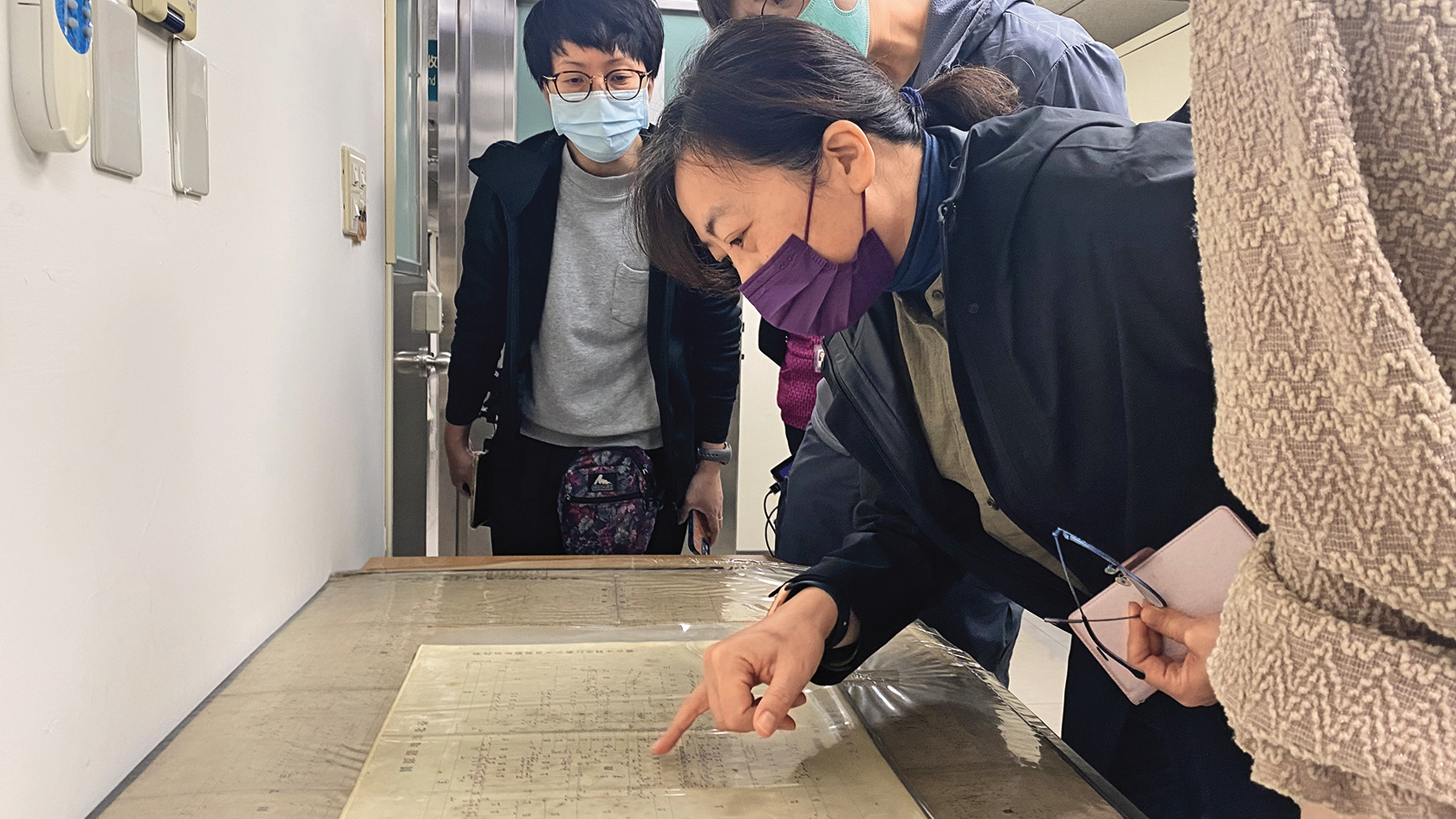 導演蕭菊貞（右前）從各種檔案資料尋找「小欣欣豆漿店」店址。（牽猴子提供）