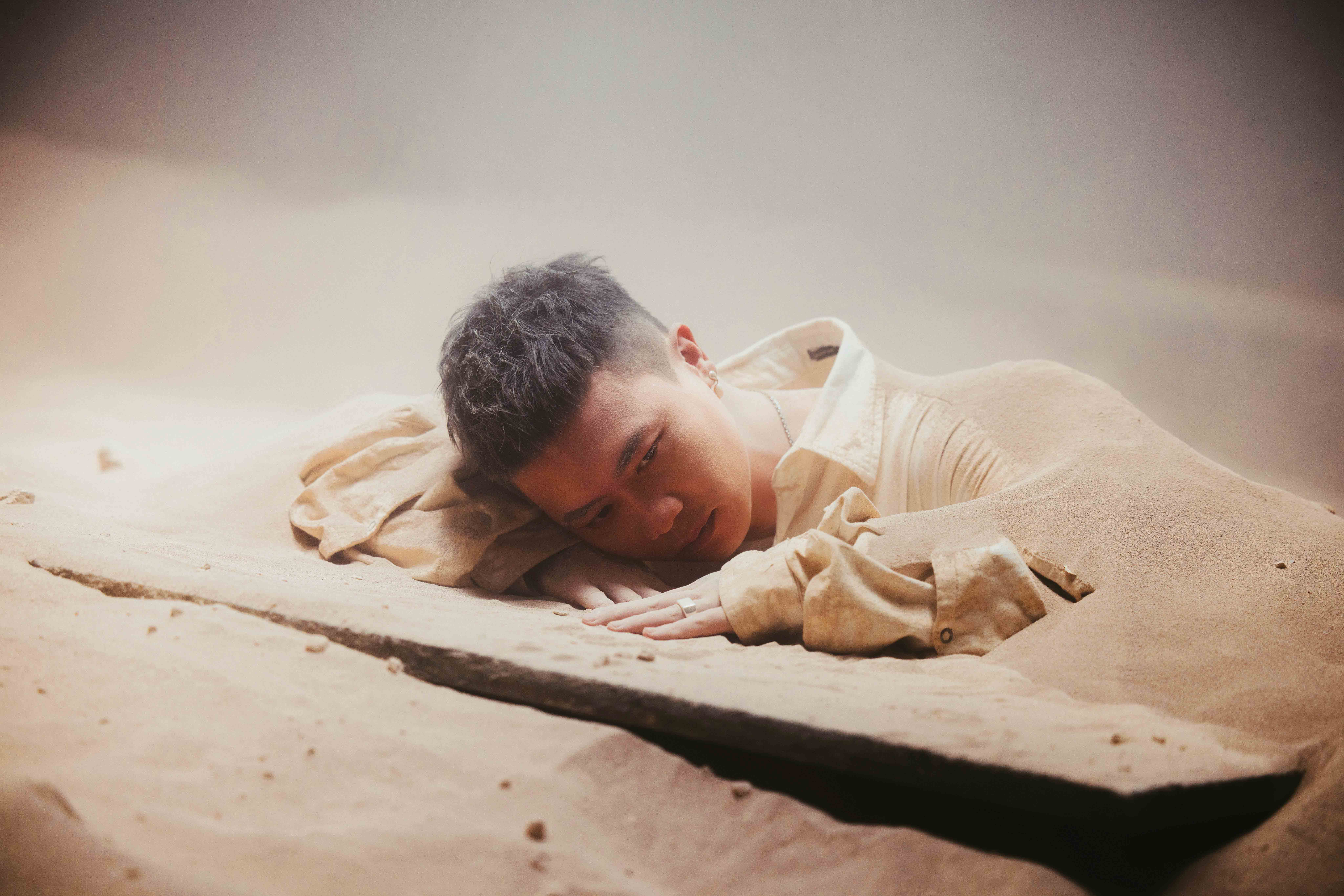 蕭秉治拍攝MV〈孤獨不是罪〉，被15噸沙子狂往身上倒。（相信音樂提供）