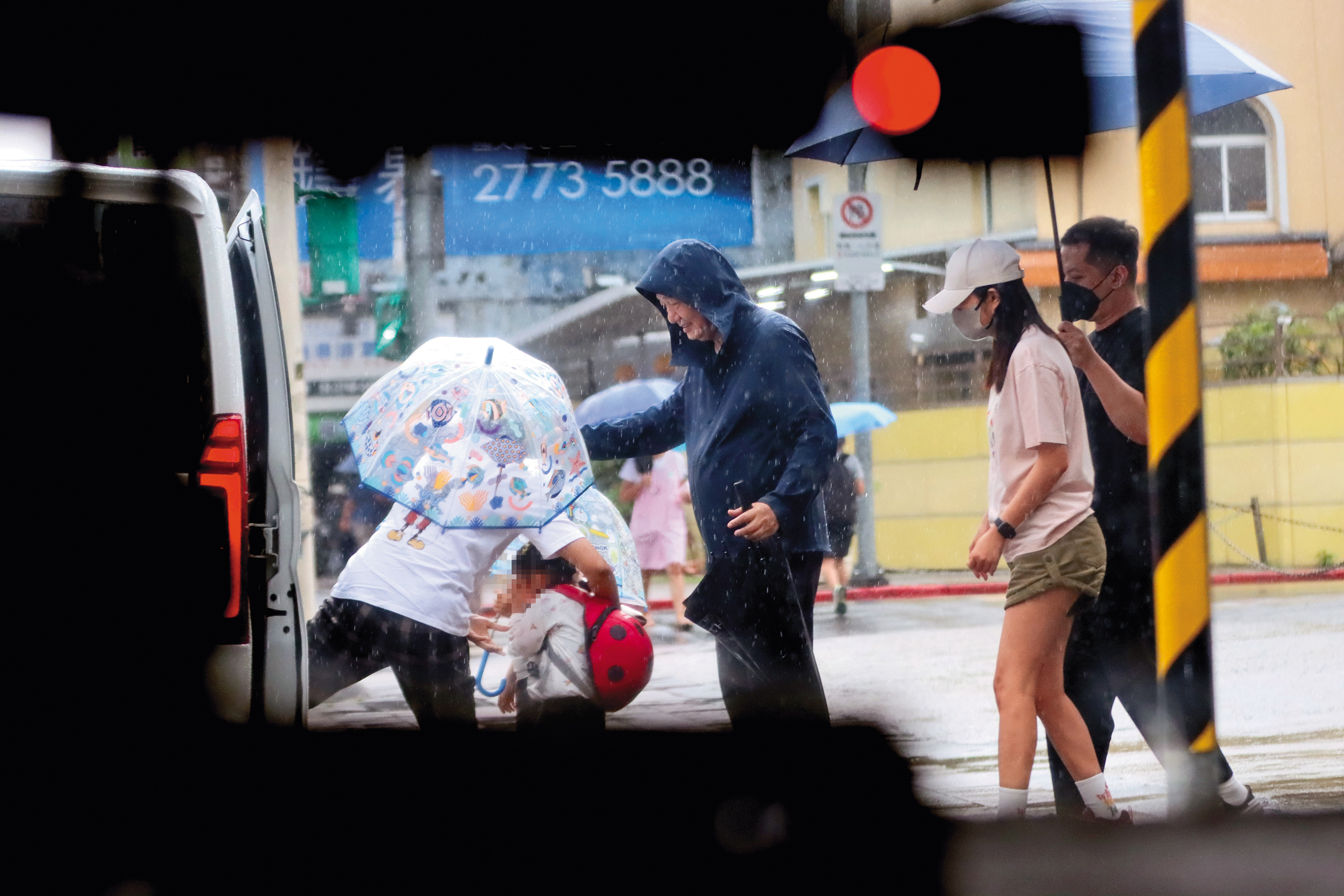 8/15 16：21 移工（左一）先把未滿4歲的妹妹抱上車，幼兒園師長（中）也來照應。