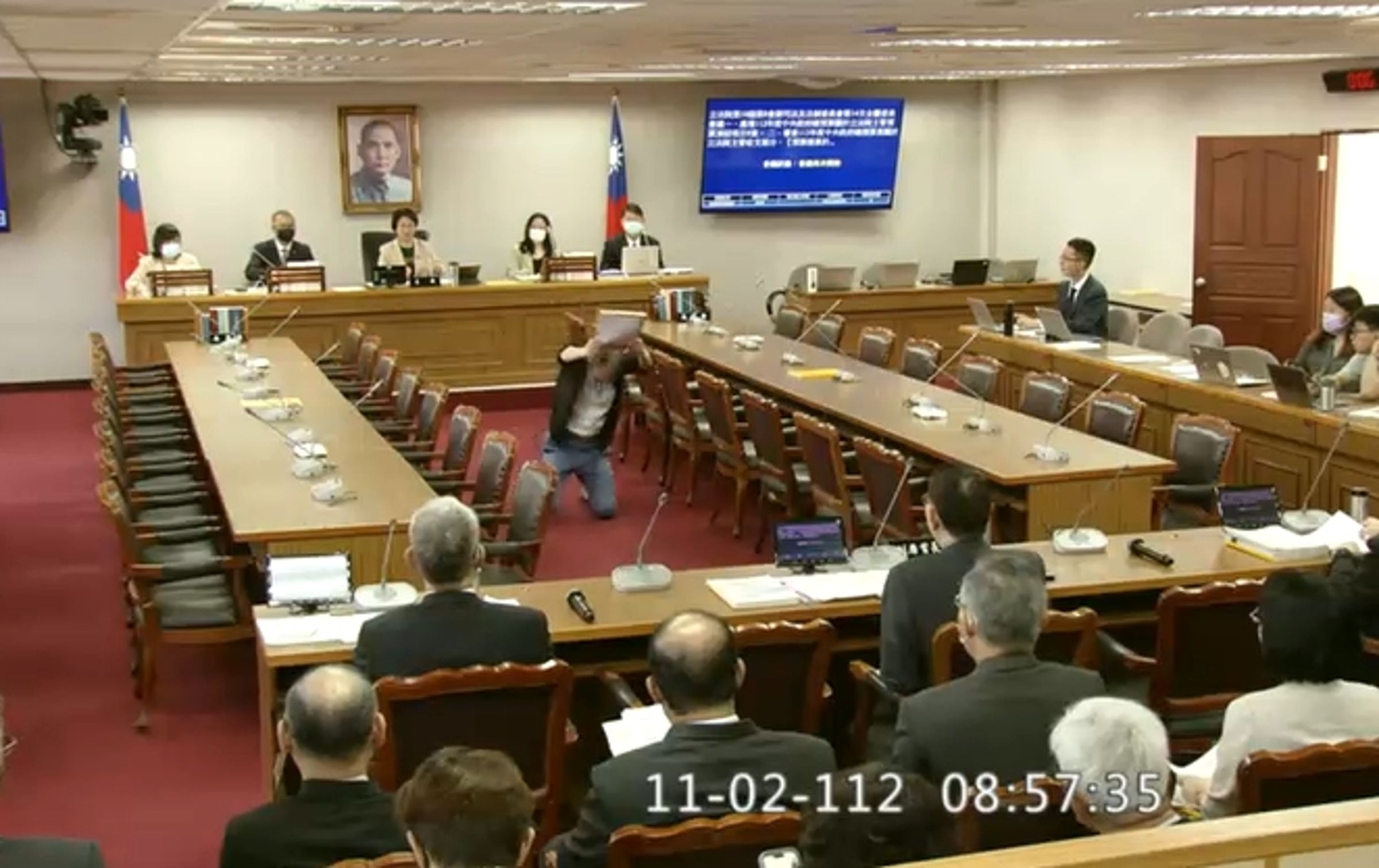 立法院公報處一名職員在委員會審查預算時,突跪地向祕書長林志嘉陳情。(翻攝畫面)
