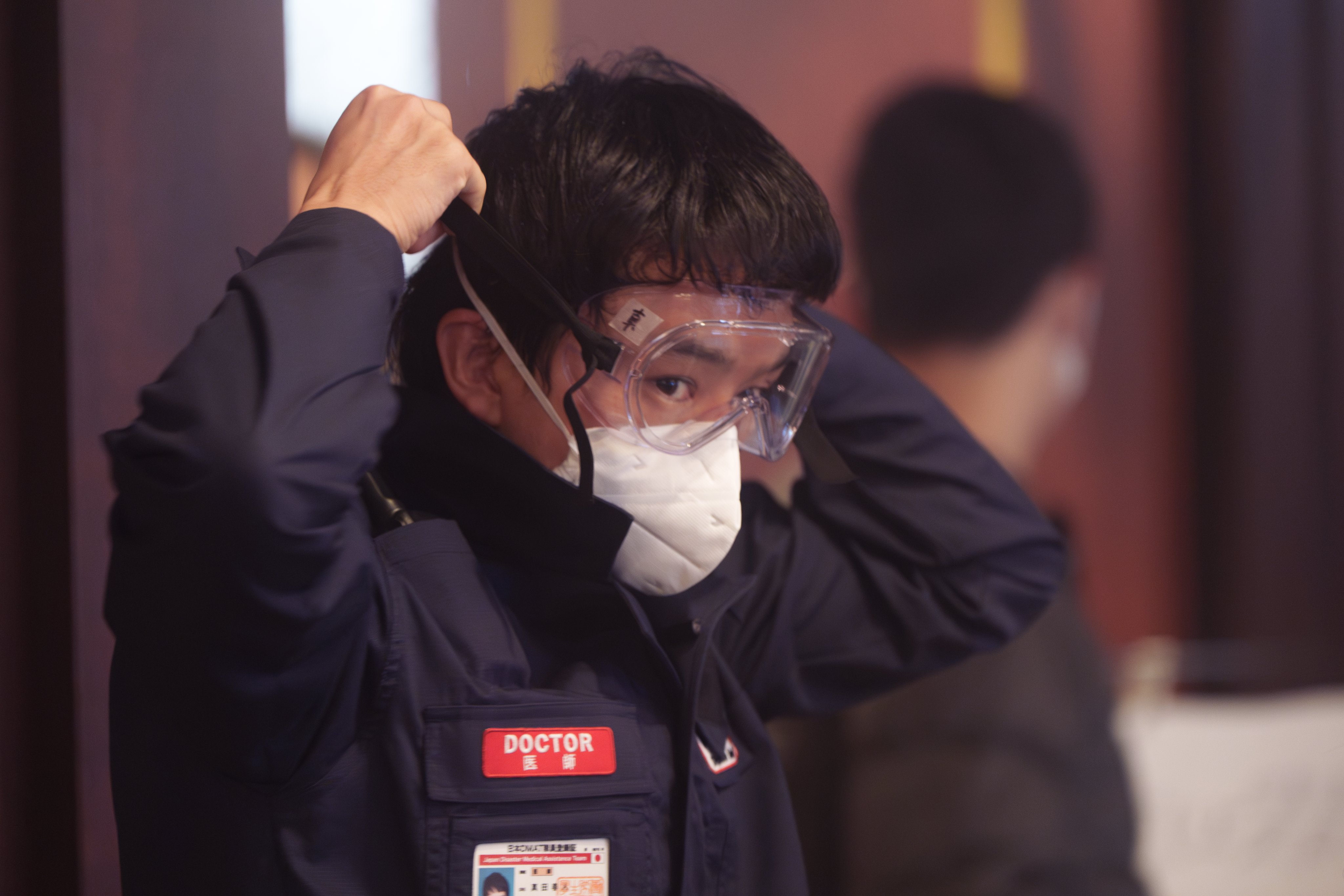 日星池松壯亮在片場堅持長時間佩戴N95口罩，休息時間也不取下。（翻攝《戰疫前線》官方X）
