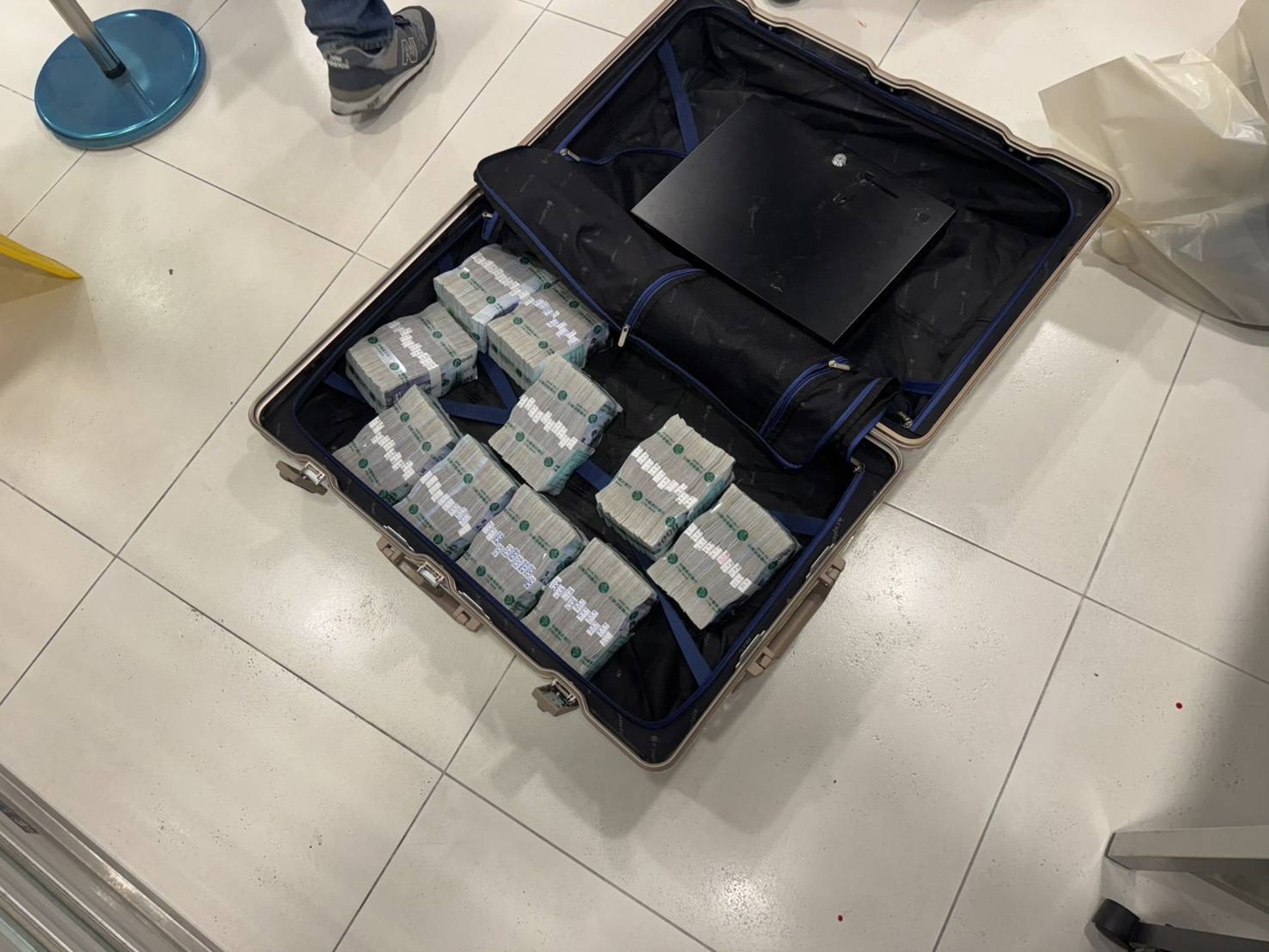 搶匪挾持保全到金庫迅速搜刮1,000萬元的現金，裝進行李箱裡。（翻攝畫面）