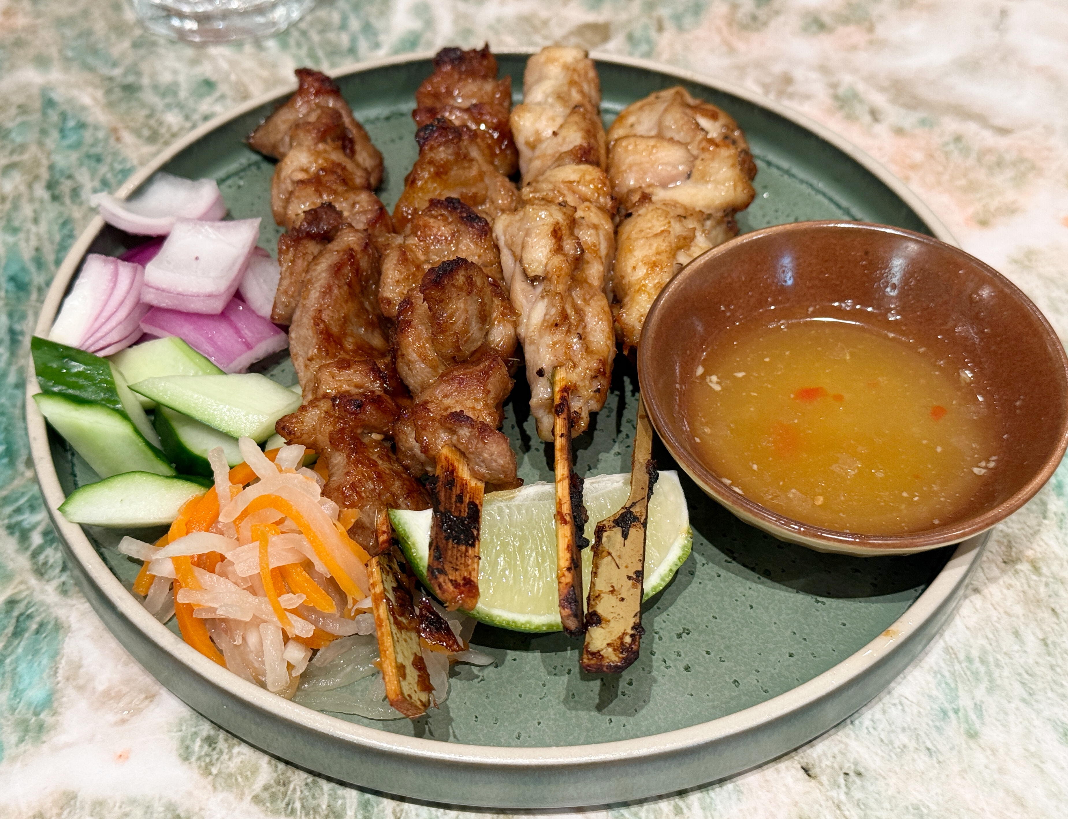 「河內烤肉串拼盤」選用雞腿肉、豬梅花以秘製香料醃漬，燒烤至外層微焦、香氣撲鼻，搭配生菜與百香魚露。（690元／份）