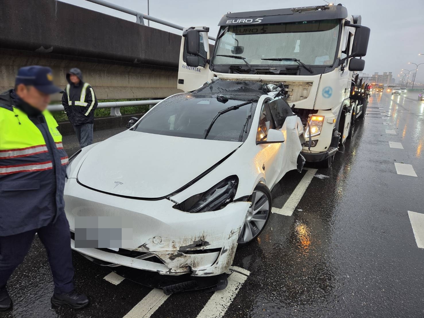 何男駕駛的特斯拉自撞國道護欄，待援時又遭後方聯結車追撞。（翻攝畫面）