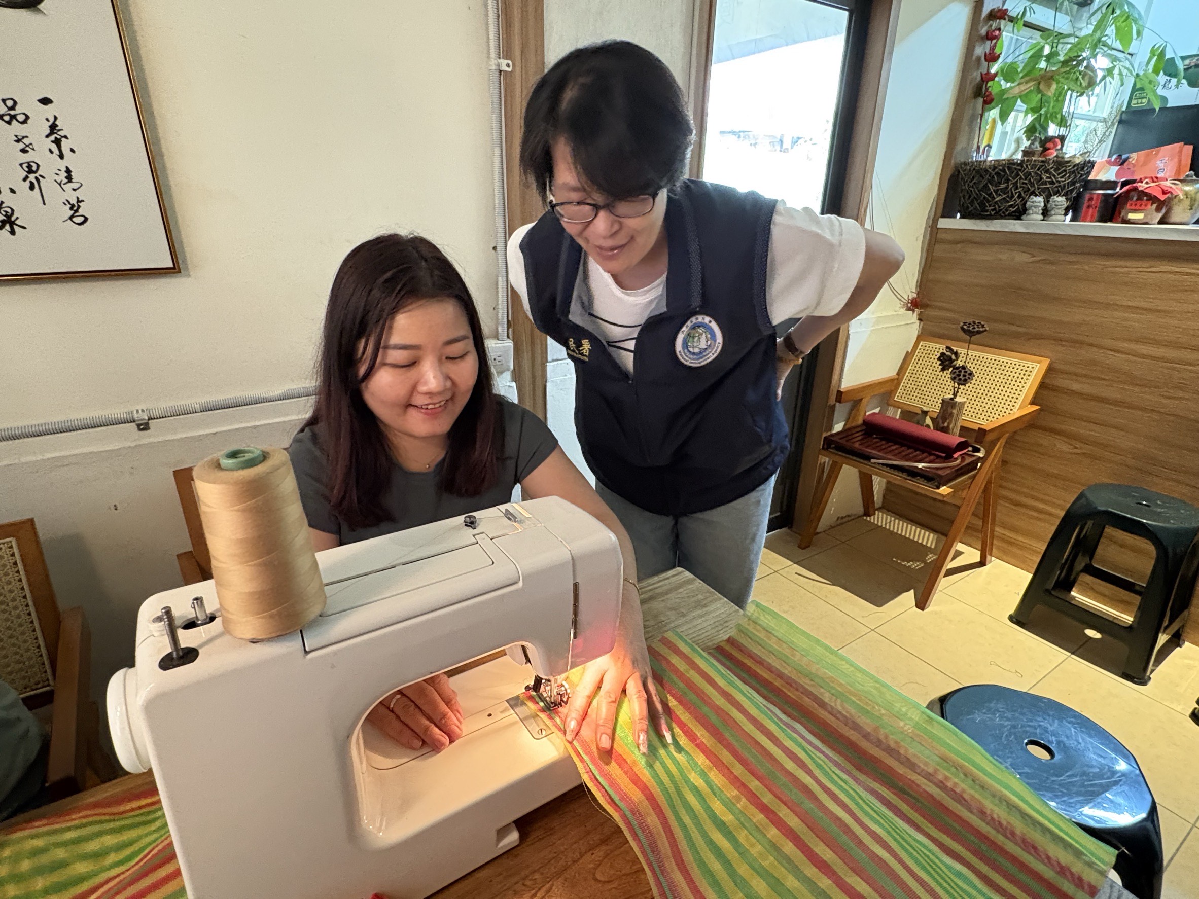 新住民紅青（左）開心地製作屬於自己的茄芷袋，嘉義市服務站主任黃艷薰（右）在旁觀看。（移民署提供）