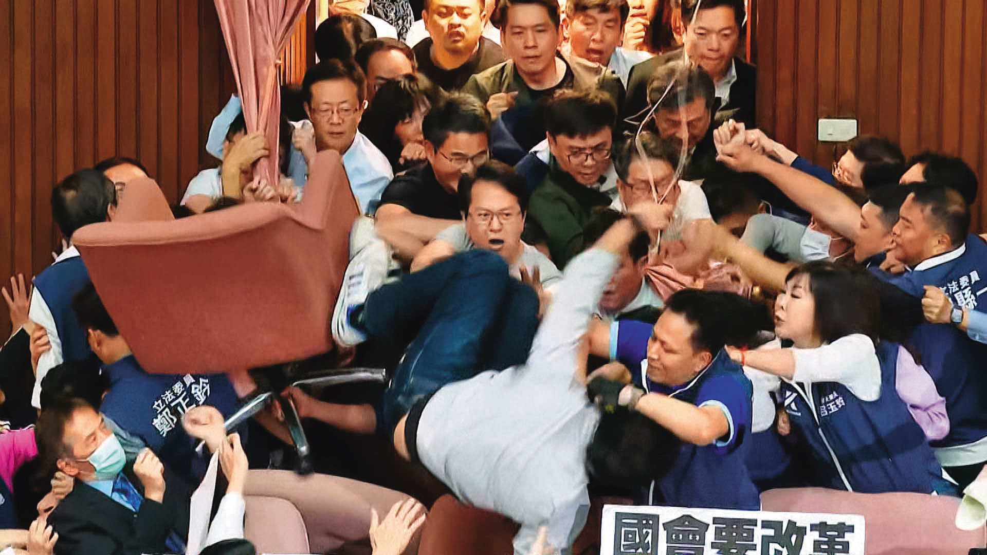 民進黨從正面進攻主席台，多人因此摔傷。圖為沈伯洋從主席台摔落。（翻攝鏡新聞）
