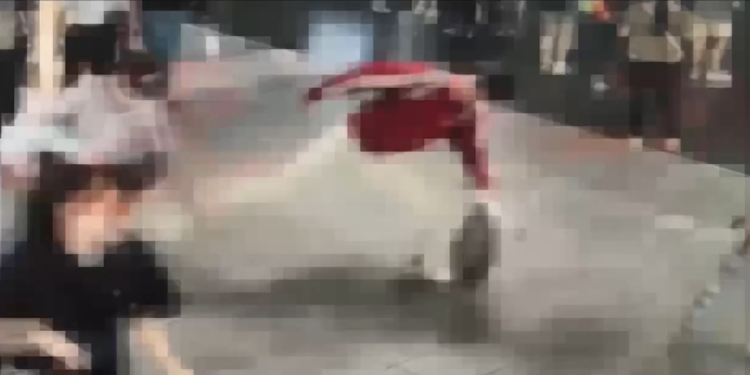 身穿紅衣的怪男，突然不明原因持傘攻擊女路人，還朝女路人連踹好幾腳。（翻攝畫面）