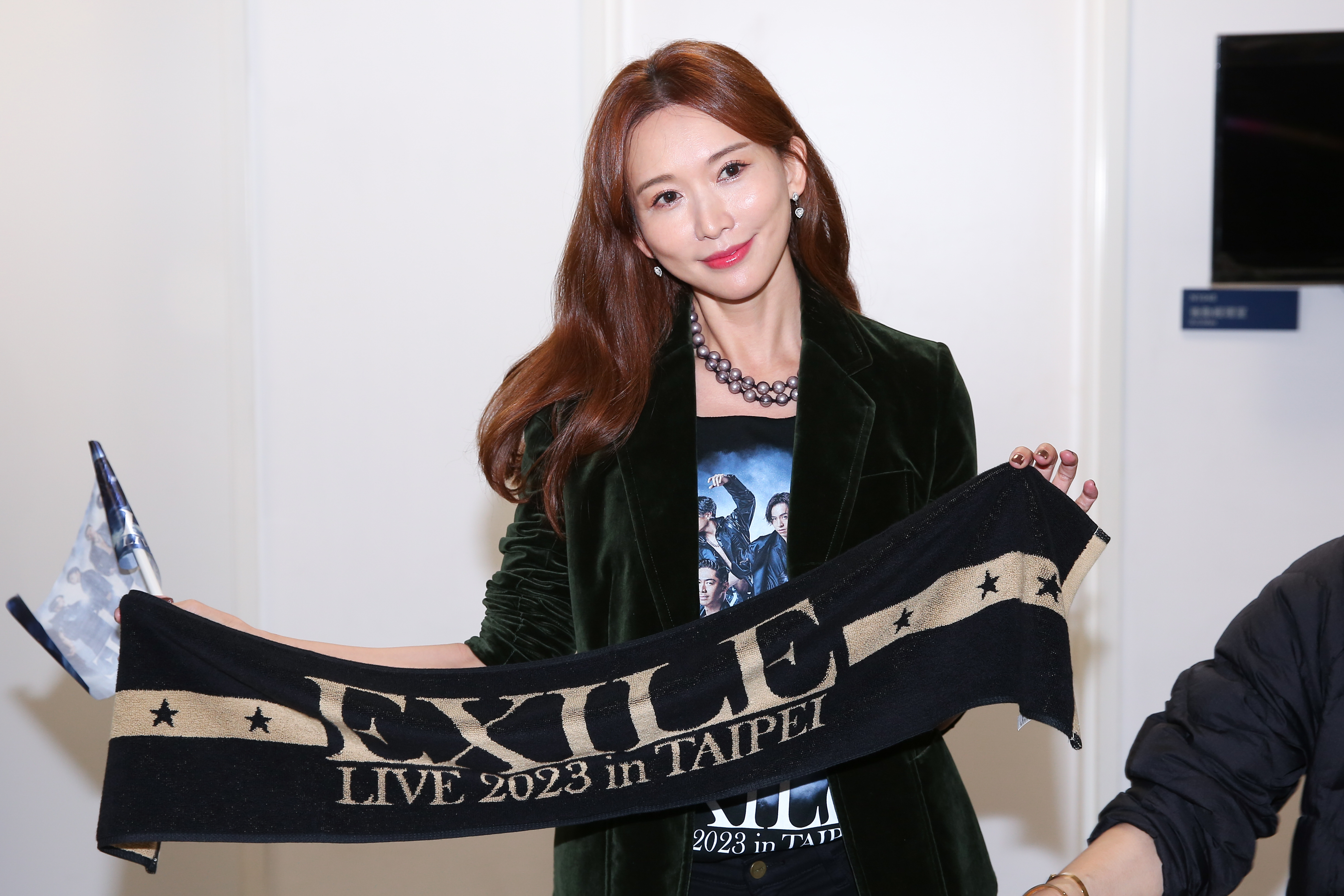 林志玲穿著演唱會周邊T恤，手持應援旗與手幅毛巾為老公AKIRA應援。