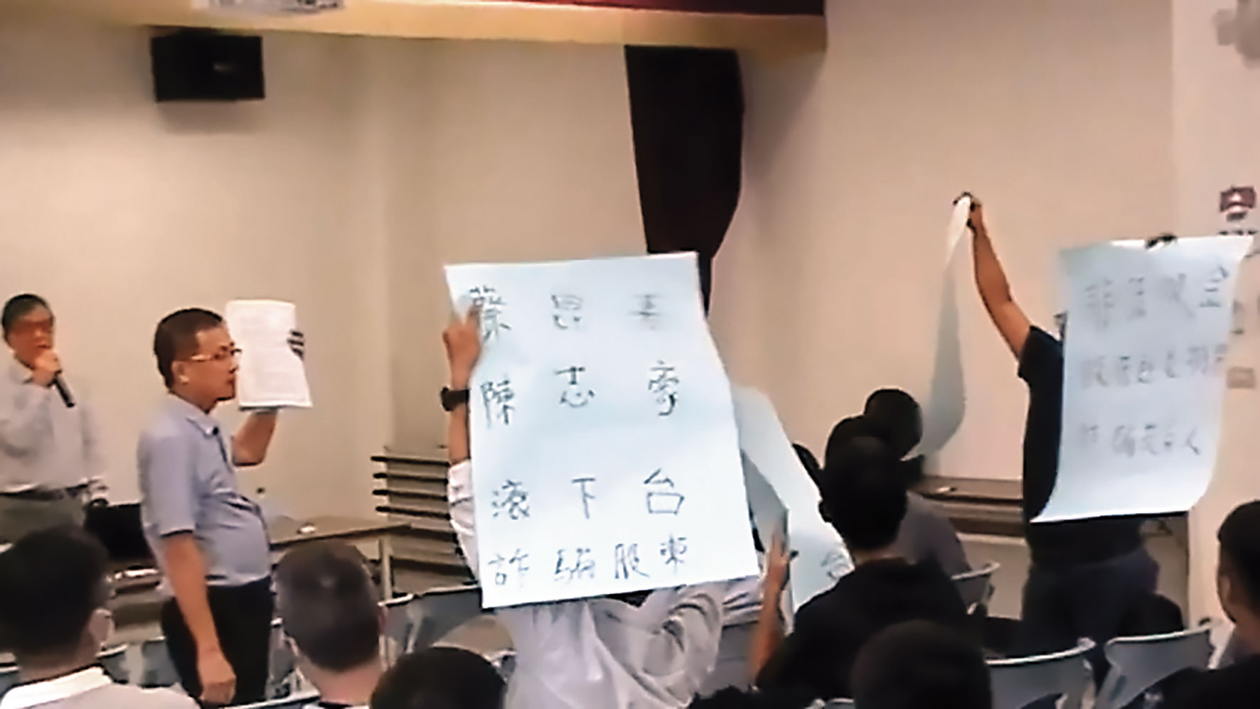 創心醫電股東會時,大股東持大字報控訴蔡昆熹詐騙投資人。(讀者提供)