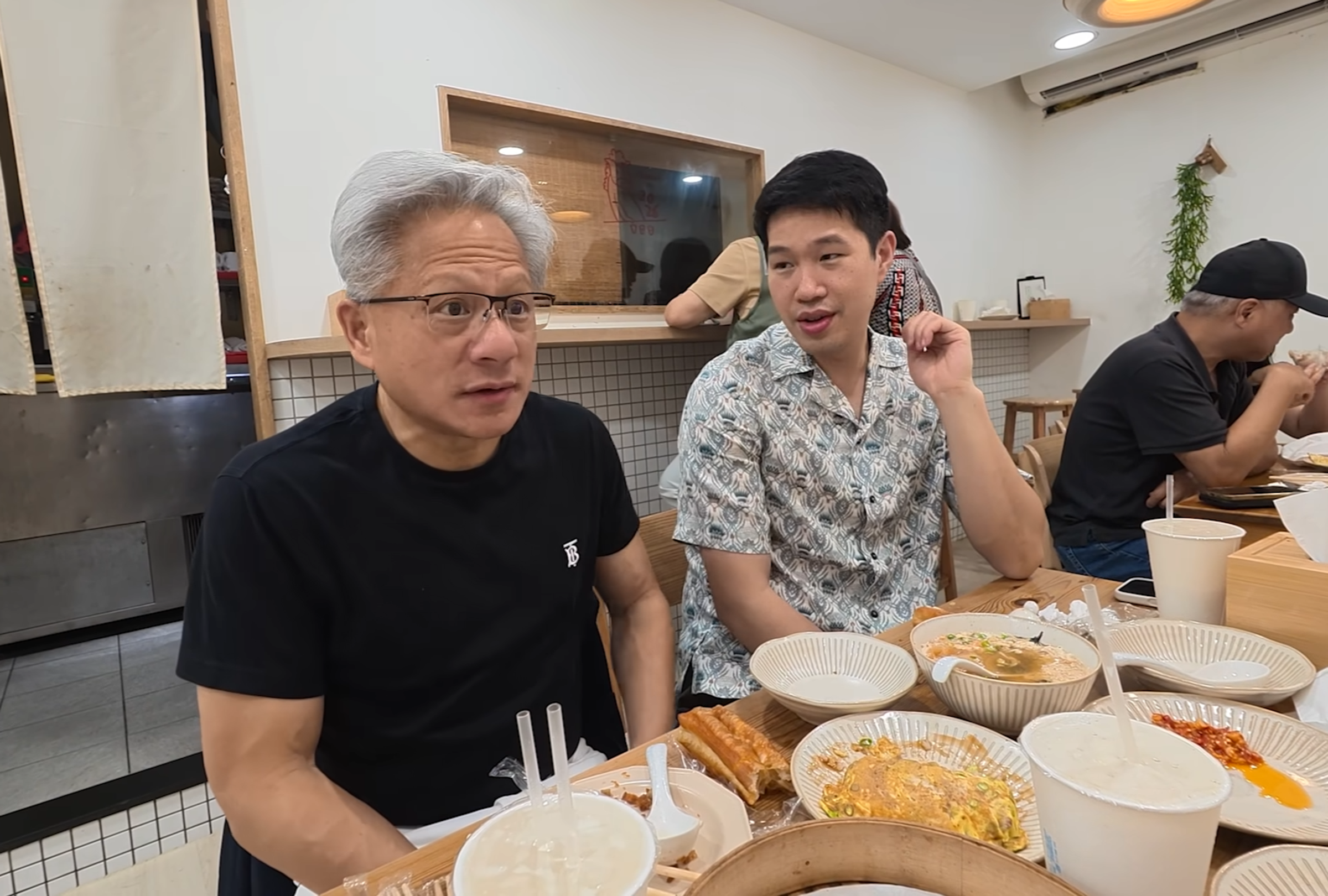 黃仁勳(左)一邊享用台灣早餐,一邊向眾人分享當年如何透過黃頁電話簿聯絡台積電,展開與張忠謀的合作緣分。(翻攝Lex Fridman YouTube)