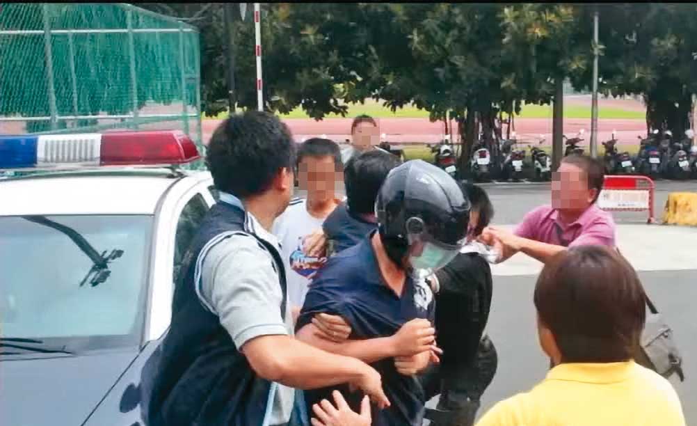 縱火的情侶檔被帶回警局時,黃家親友氣憤追打呂男。(翻攝蘋果新聞網)