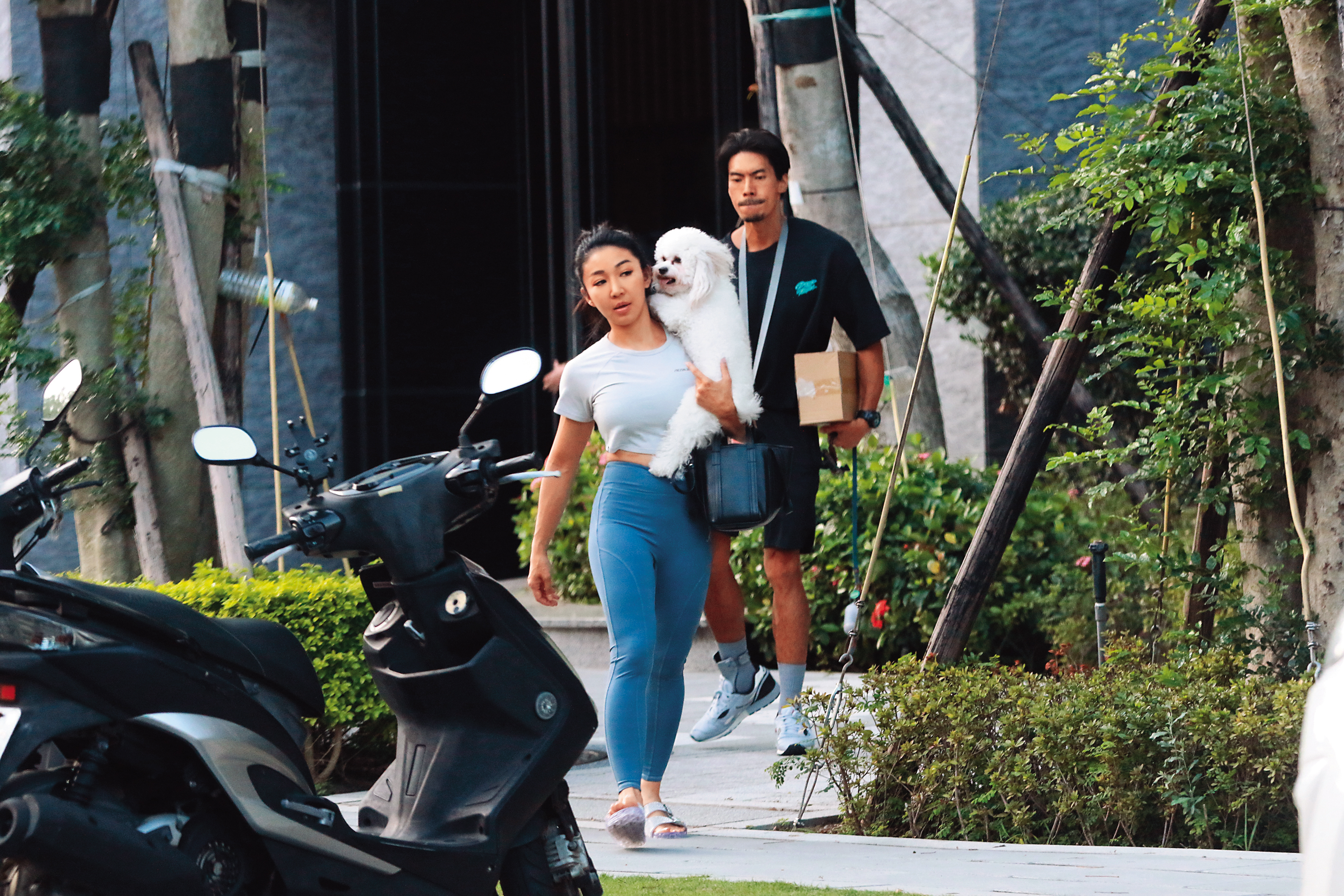 10月13日14時57分，筋肉媽媽穿著拖鞋扛著一隻狗，筋肉爸爸拿著一箱包裹一同出門。