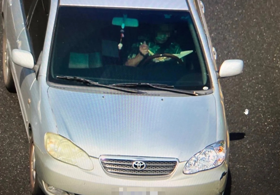 有駕駛行駛在國道上時用左手托便當、右手拿筷子夾菜，不顧危險大口吃便當。（翻攝畫面）