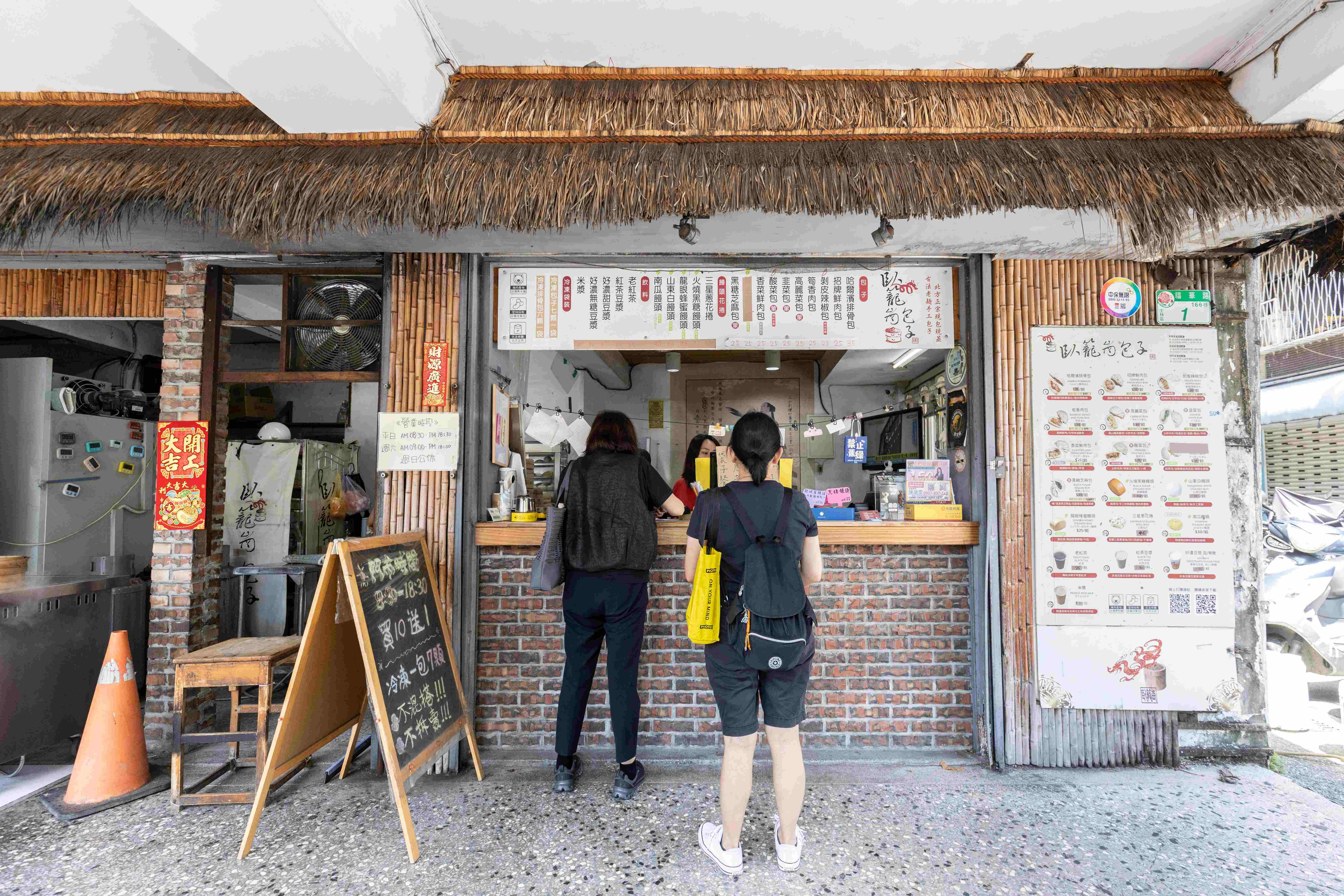 「臥籠崗包子」的店面以茅草頂裝飾，和店名相映成趣。