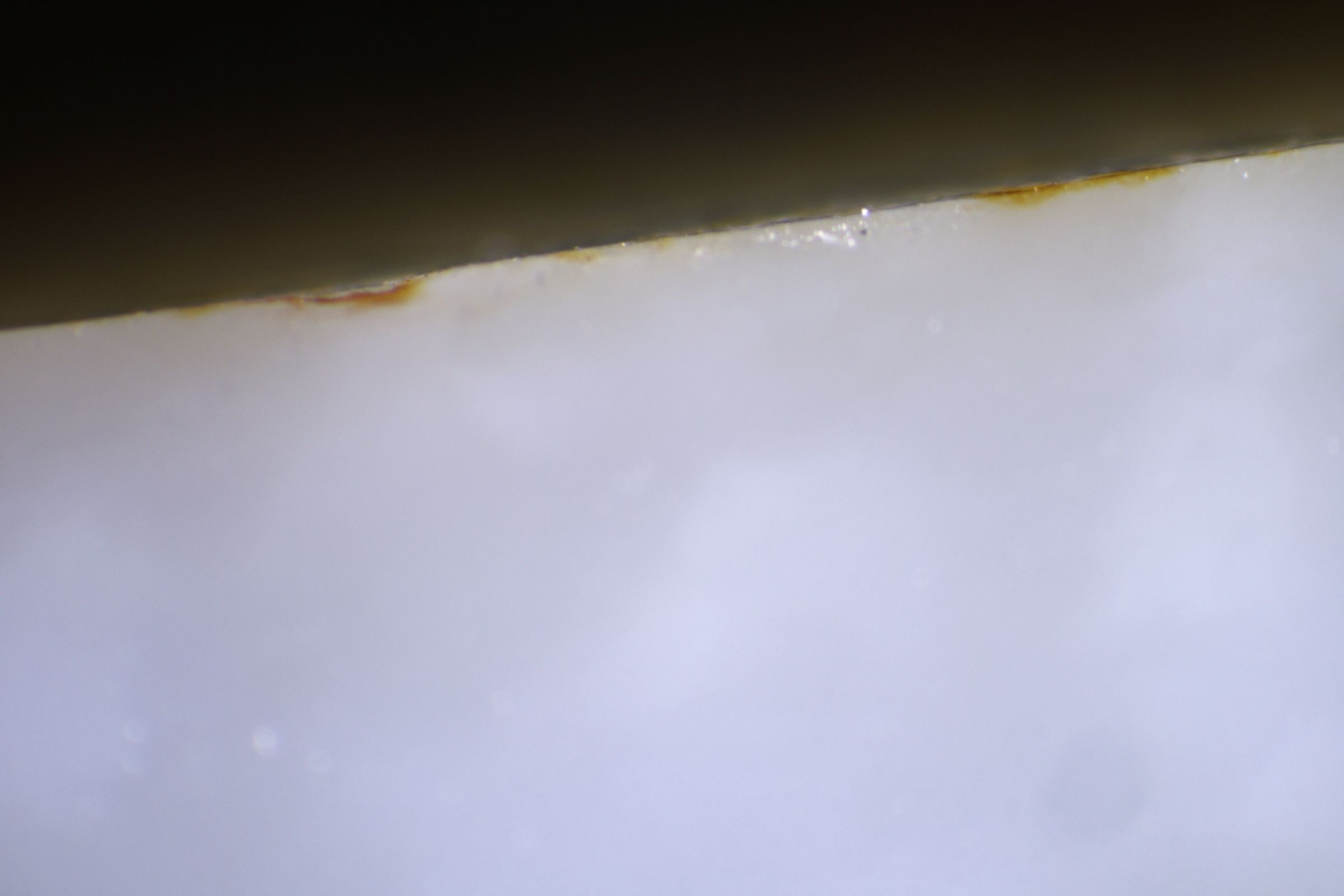 一件玉料被切成無事牌，側面露出極薄的表層色帶，才得以觀察顏色沁入的深度，據此判定是假皮色。（讀者提供）