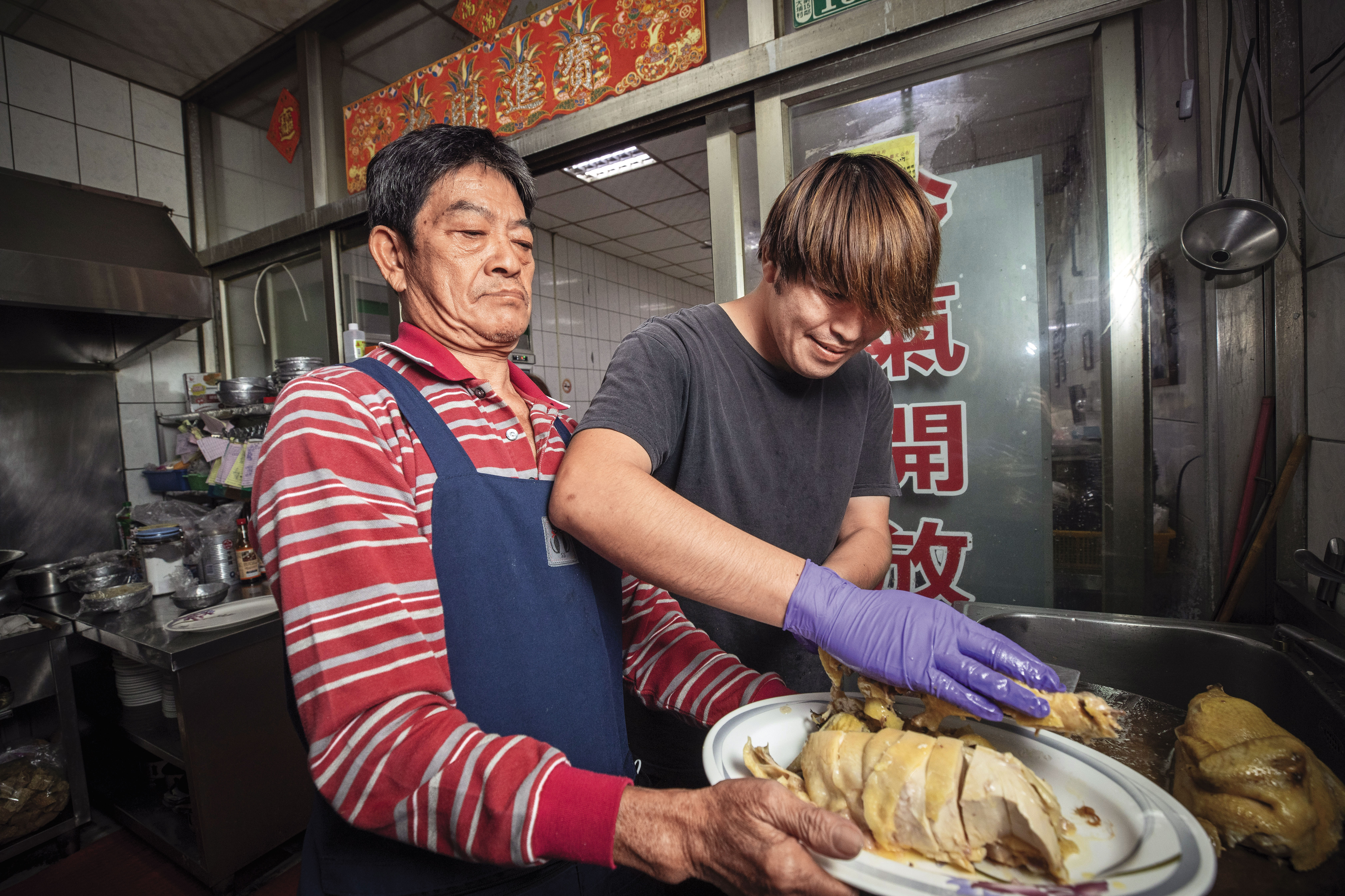 自家養的白斬雞亦是佳香的招牌菜，江明苓老公羅吉鎮（左）與次子羅偉壬（右）負責砧板備菜。