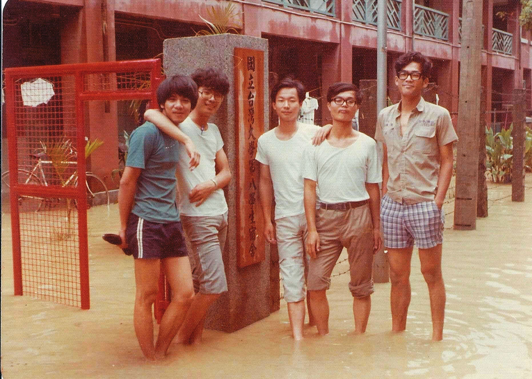 鄭明典（中）深知防災重要，每逢颱風及大雨，總想方設法發出警訊。圖為他於台大就讀時遇到水災，與同學在宿舍門口合影。（鄭明典提供）