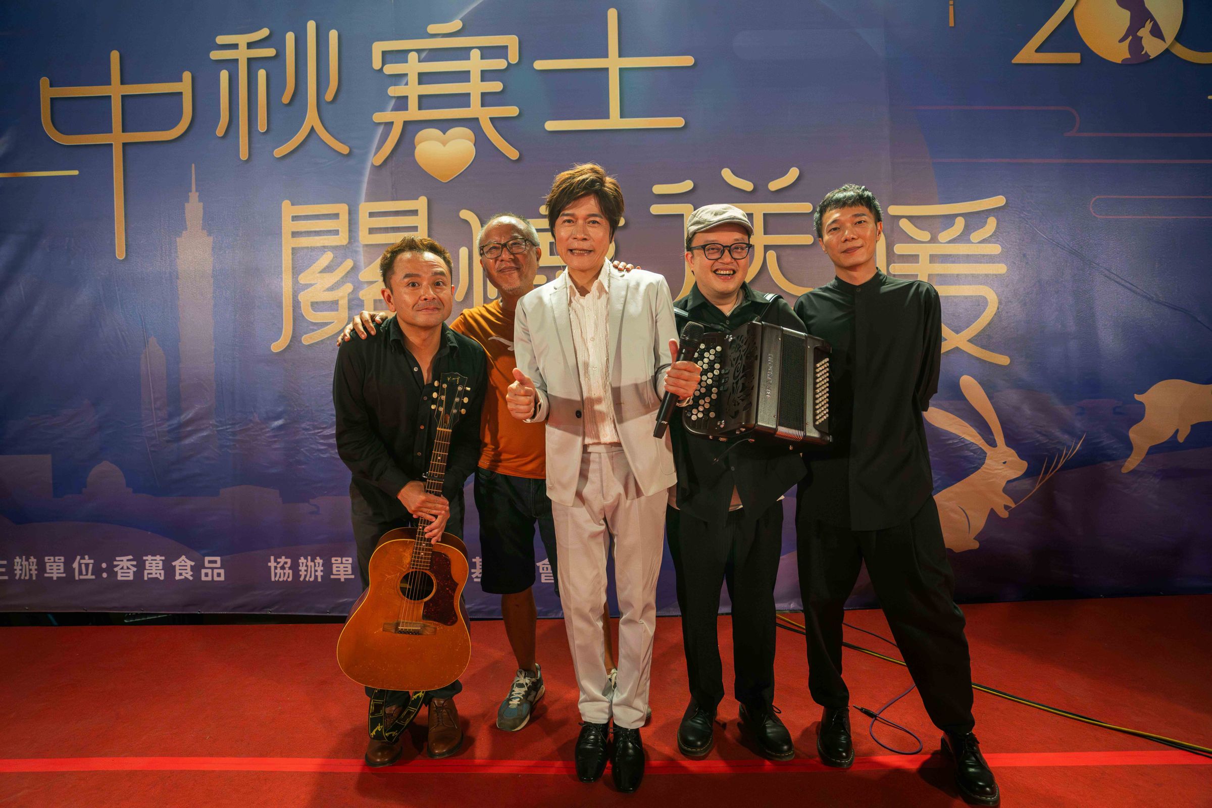 鍾孟宏（左二）執導的《餘燼》辦桌場面邀洪榮宏（中）獻唱，台上樂團伴奏之一為該片配樂盧律銘（右一）。（本地風光提供）