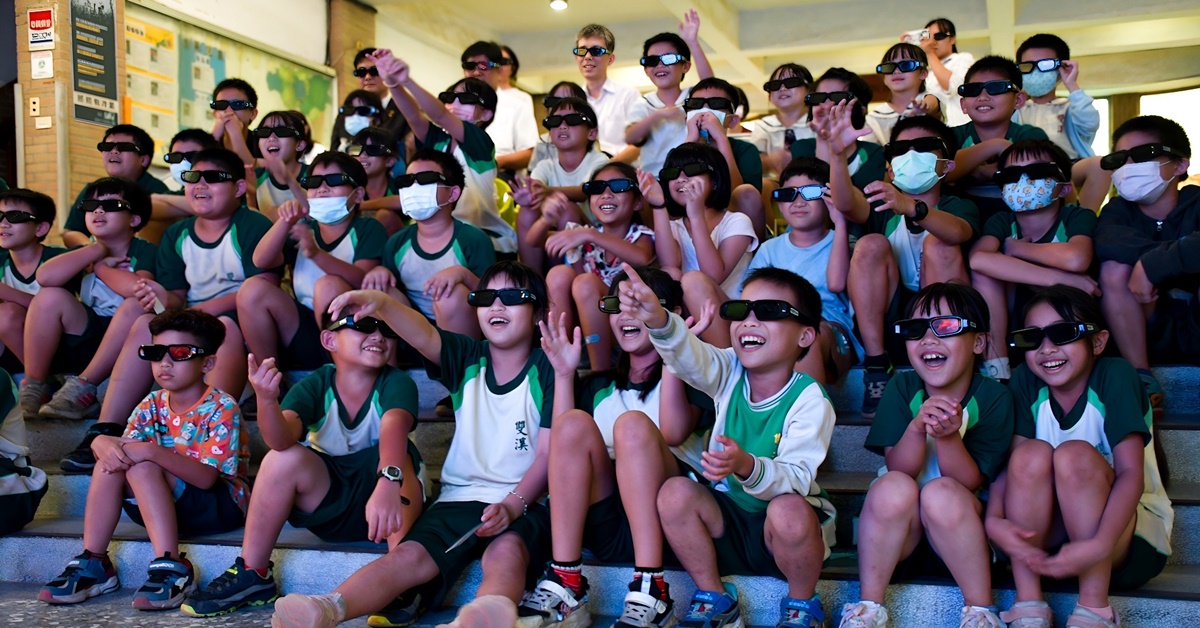 孩童們開心地坐在台階上戴上特製3D眼鏡，觀賞電影車帶來美力台灣、台灣超人影片，體驗不一樣的上課日常！（永慶房產集團提供）