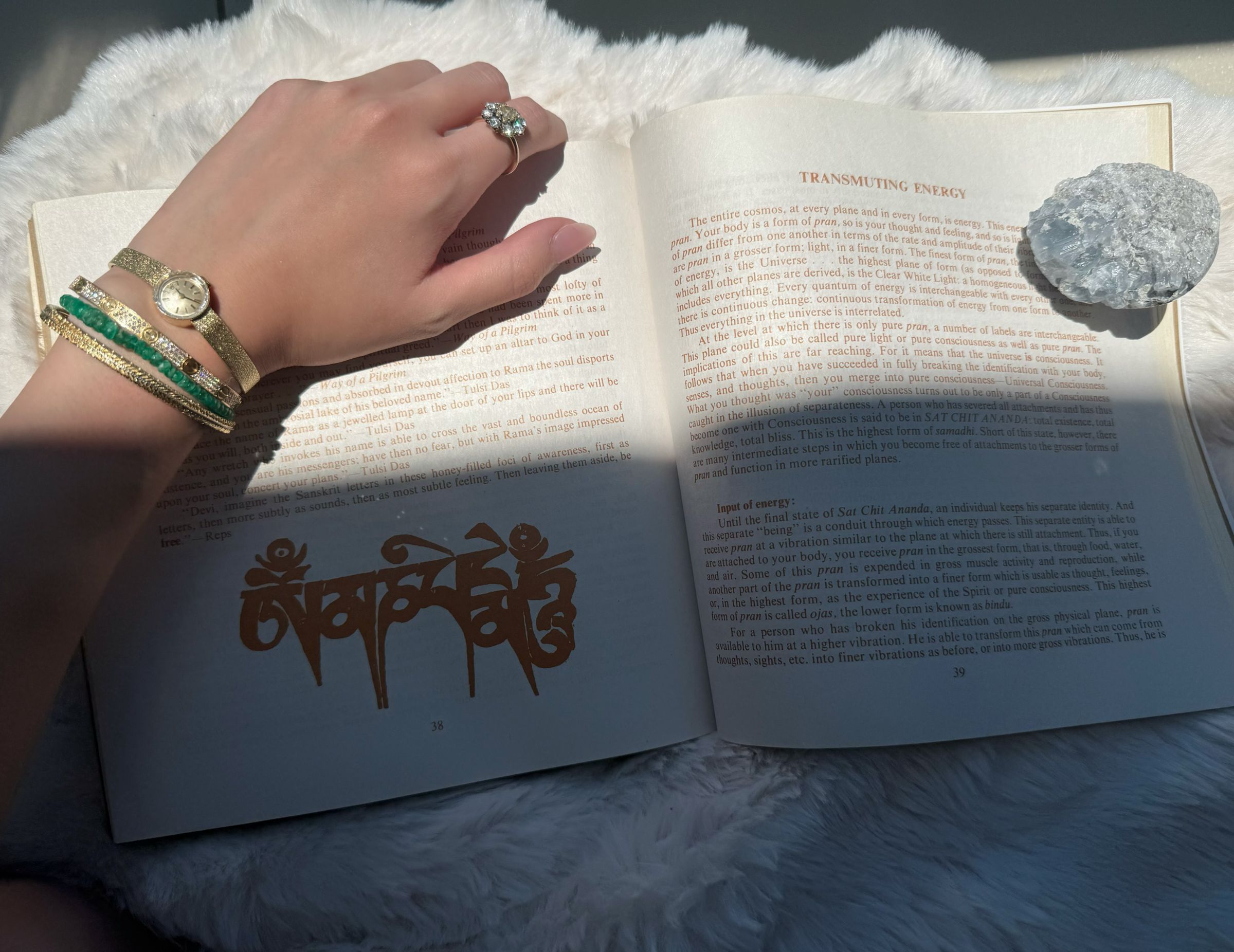 廖思惟分享閱讀瑜伽哲學書籍的照片,書頁上擺放淡藍色水晶,手腕疊戴多款金色手環與綠色珠串。(翻攝trinityliao IG)