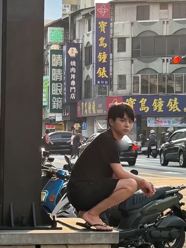 佐藤勝利穿著黑色短袖與短褲，腳踩夾腳拖，隨性蹲坐在路邊。（翻攝自instagram＠shori_sato_official）