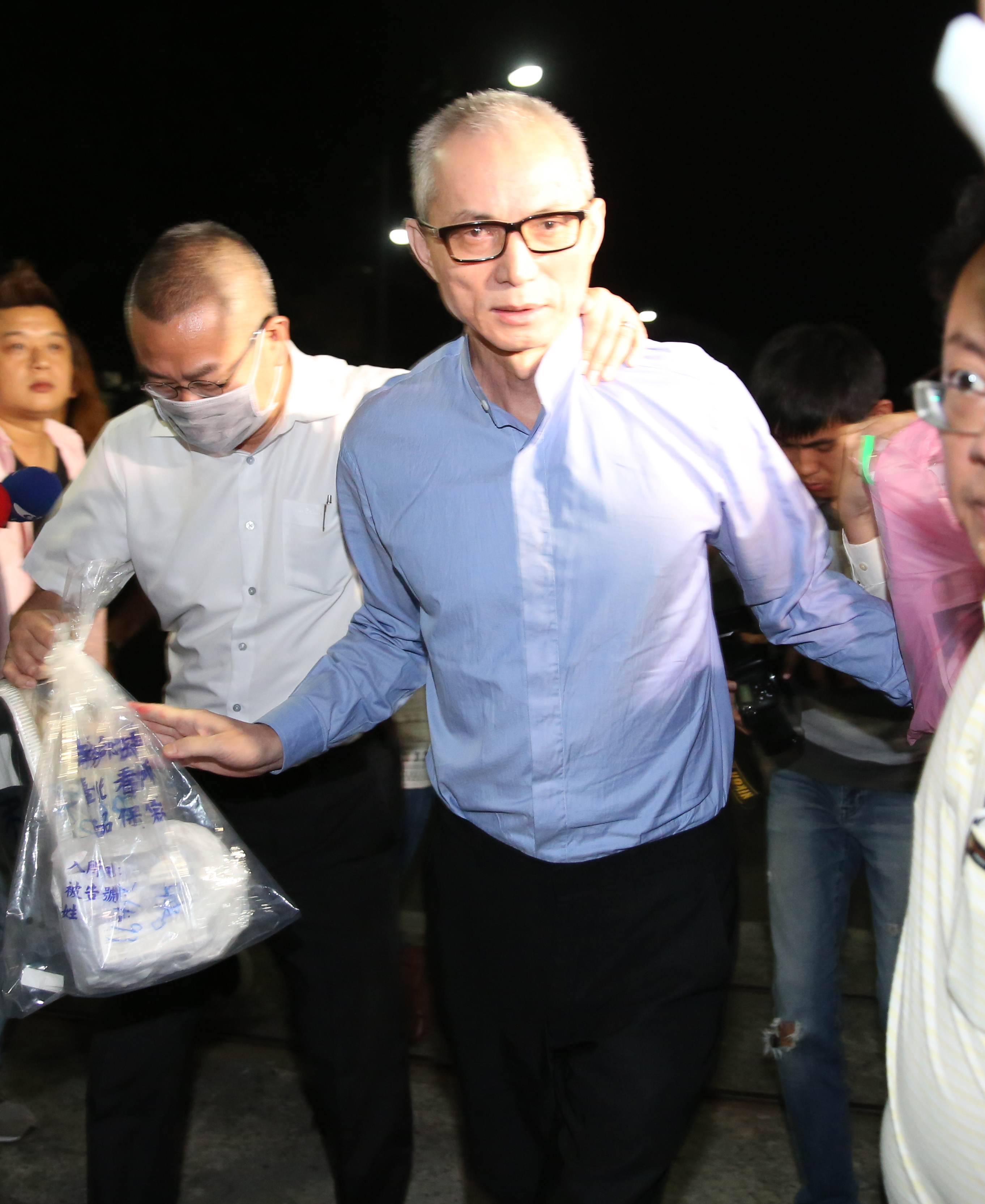 身家據傳近百億元的朱國榮以4億元交保後，左手捧粉色塑膠袋，右手拎黑鞋走出北所。