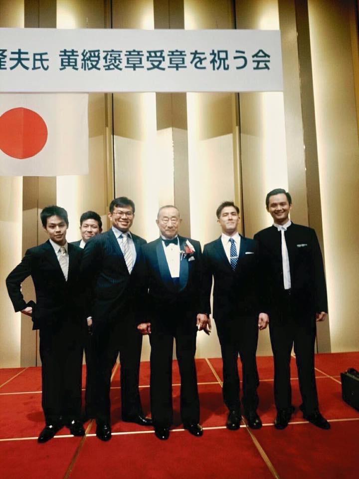 日本天皇為表彰三嶋隆夫在甜點界中的貢獻,2015年特頒發勳章,圖為天皇受贈勳章典禮。右二為小松真次郎,右四為陳世霖。(陳世霖提供)