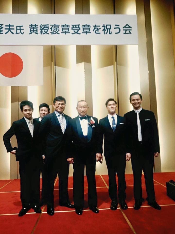 日本天皇為表彰三嶋隆夫在甜點界中的貢獻,2015年特頒發勳章,圖為天皇受贈勳章典禮。右二為小松真次郎,右四為陳世霖。(陳世霖提供)