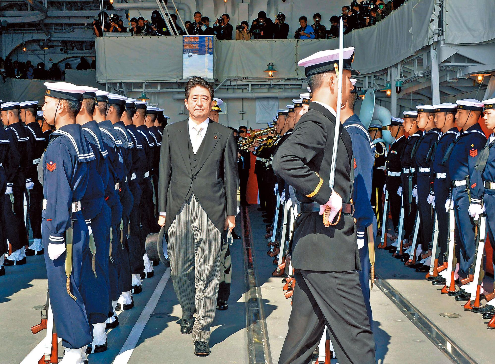 日相安倍晉三（中）將赴美會晤川普，釐清川普是否將改變華府行之多年協防日韓的慣例。圖為安倍去年底視察海上自衛隊。（東方IC）