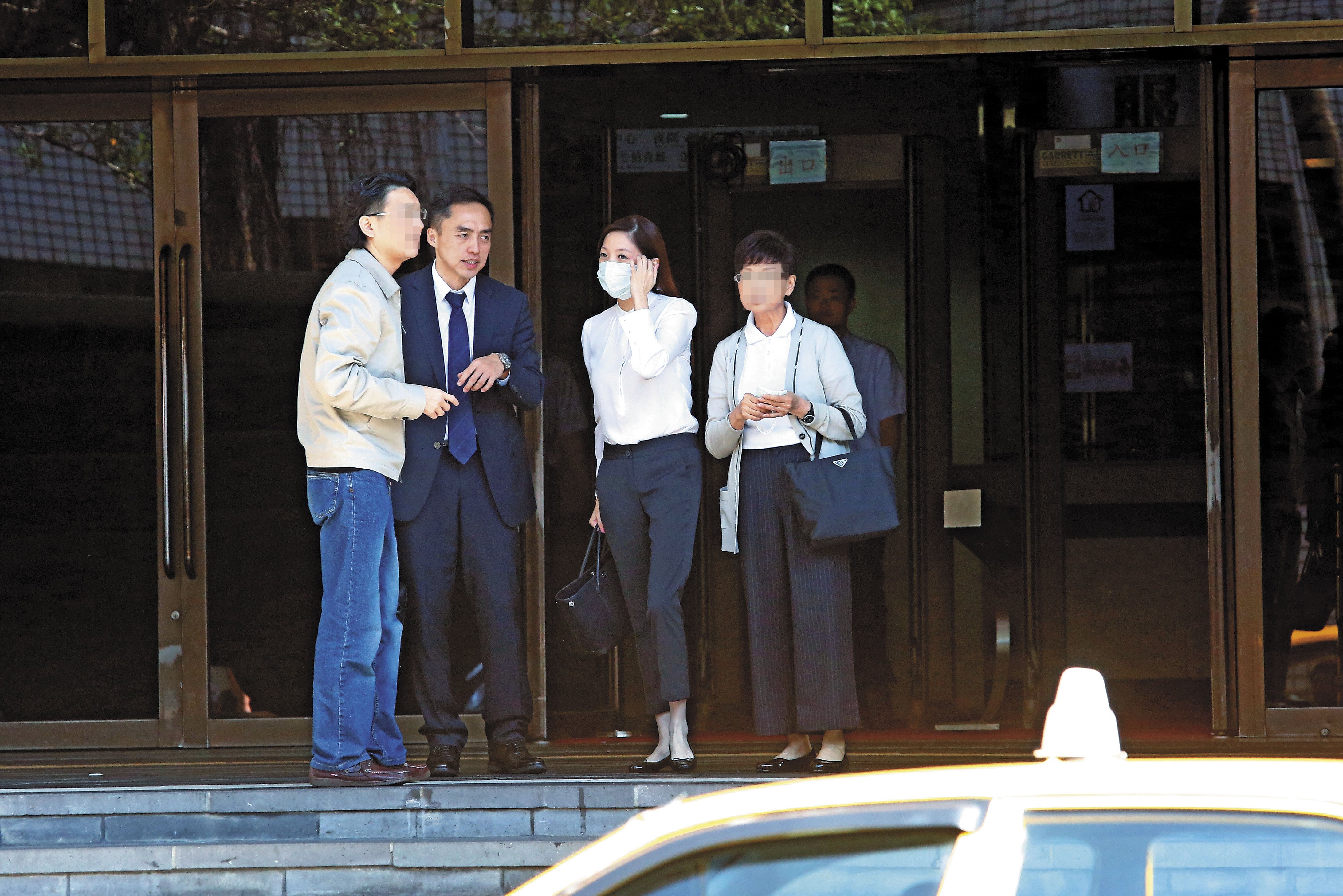 黃閔暄(右2)庭訊後戴上口罩,在律師(左2)及親友陪同下,搭計程車離去。