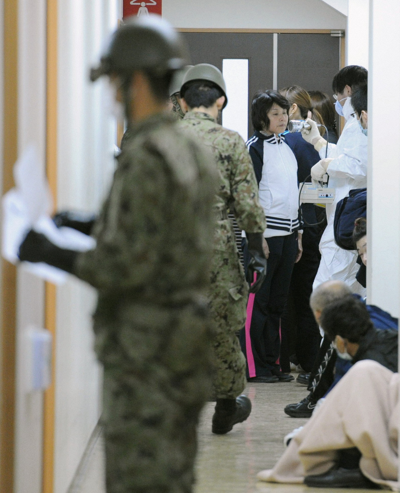 2011年3月13日,從福島緊急撤離的災民(中)在庇護所接受輻射檢查。(東方IC)