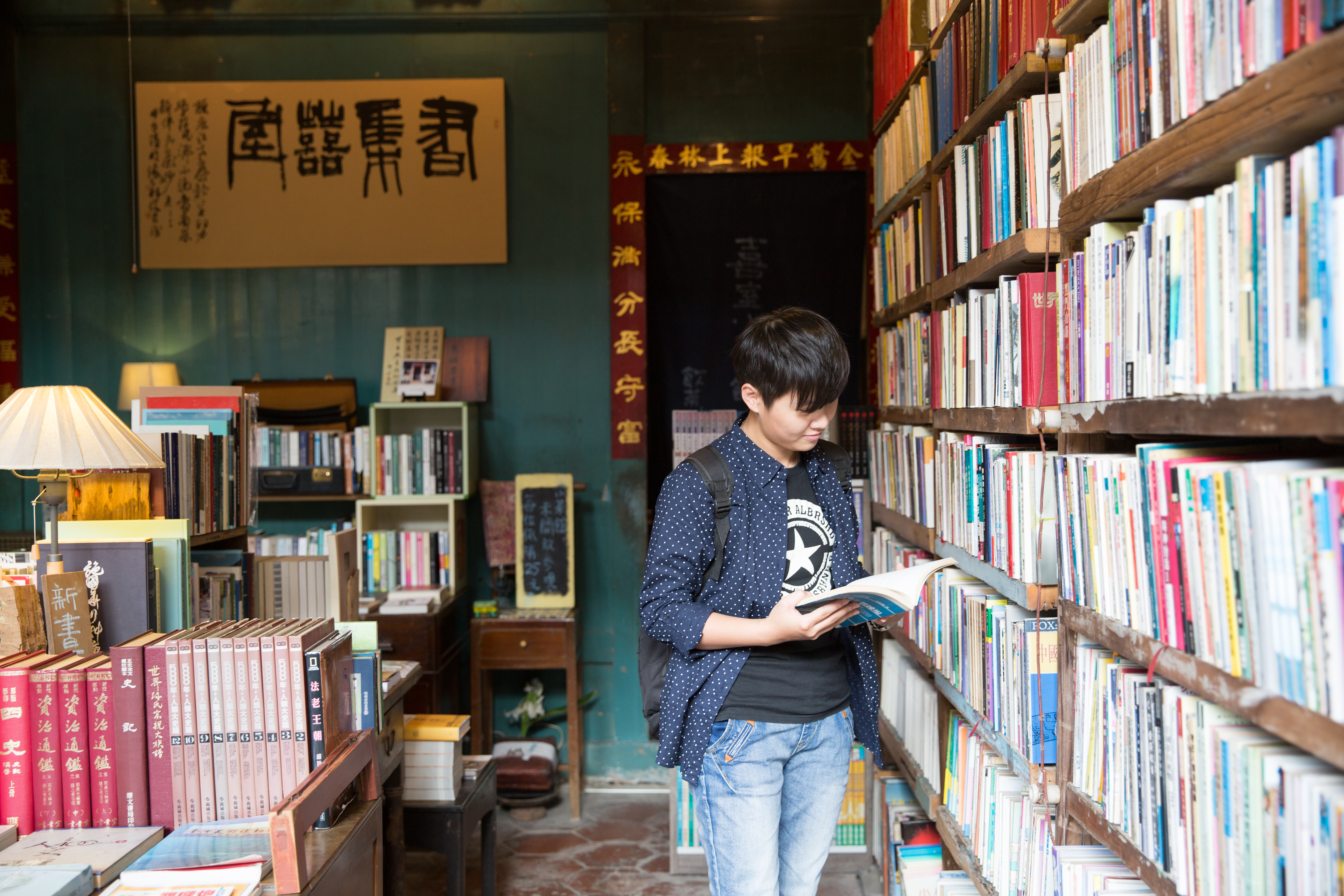 舊木書架充滿手感故事,後方門聯出自鹿港書法家黃天素之筆。