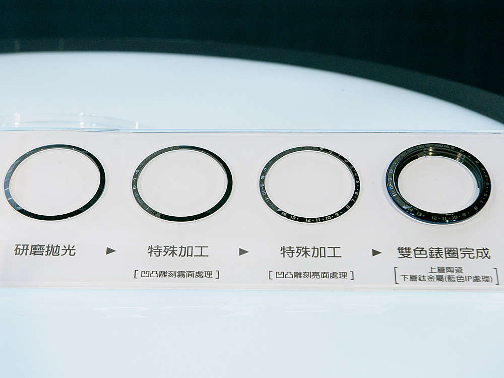 錶圈右半部的正時區指示以拋光表面搭配霧面凹下數字，而左半部的負時區指示，則是以凸起的亮面數字輔以霧面表層，光澤黑及磨砂黑交錯的雙色陶瓷錶圈，乃是以雷射微雕反覆進行霧化及拋光處理所得的迷人成果，完美展現「陰影之美」的工藝細節。